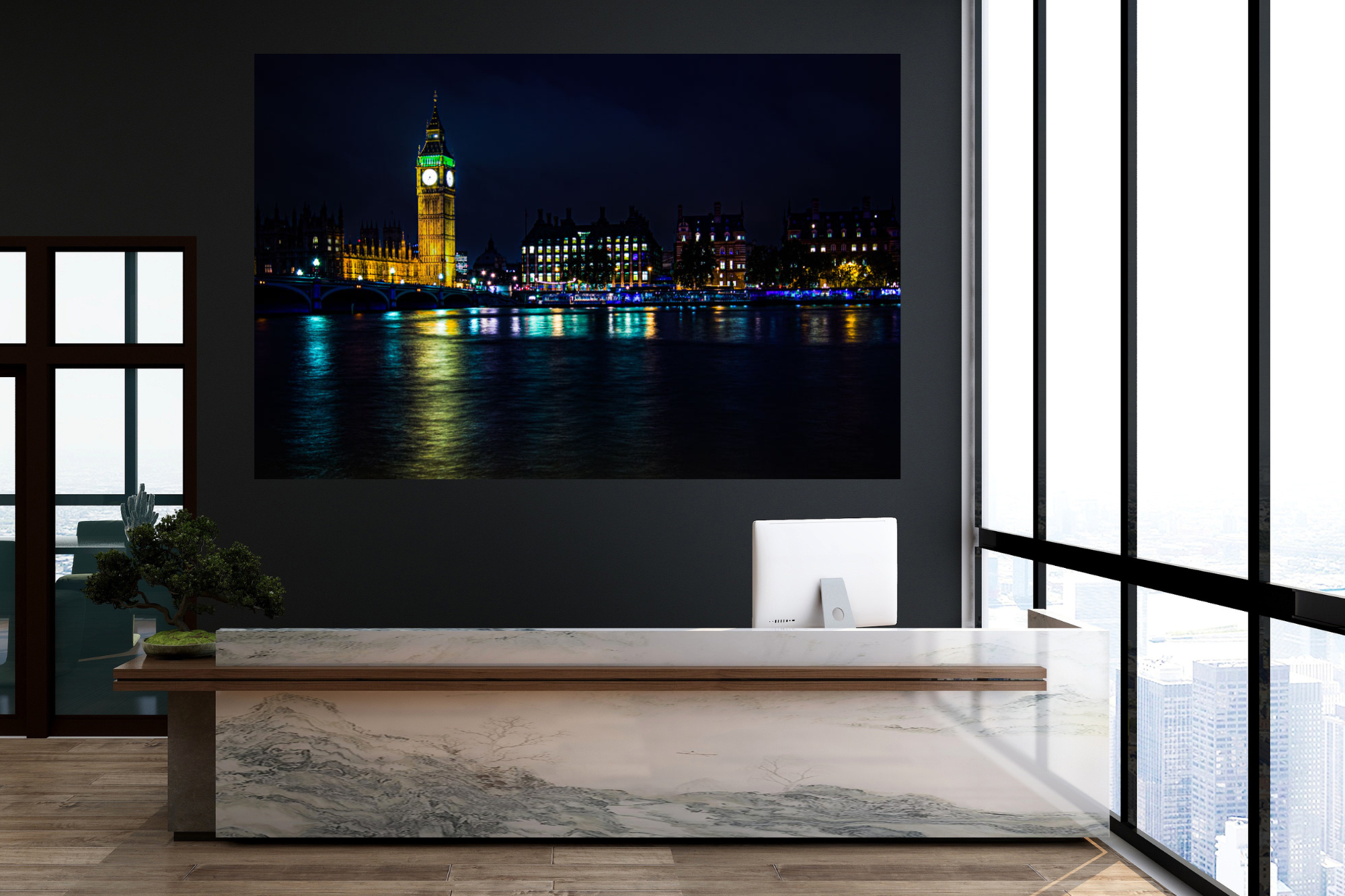 Modern office reception area with a marble desk, computer, a bonsai plant, large windows with city view, and a large art print of the London skyline at night, featuring Big Ben and the River Thames.