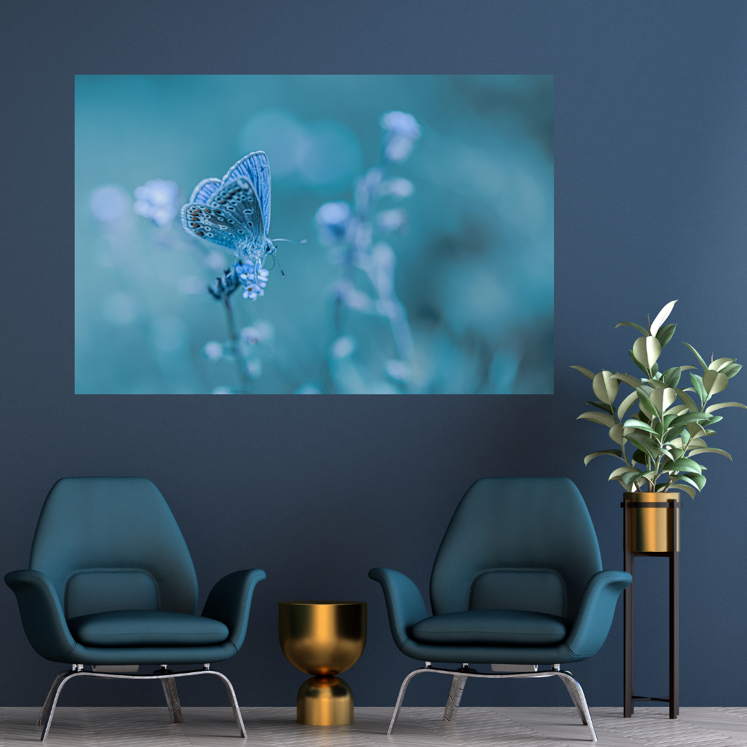A living room with dark blue walls, featuring two teal armchairs, a gold-colored side table, a tall plant in a gold pot, and a large wall art of a blue butterfly on a blurred background.