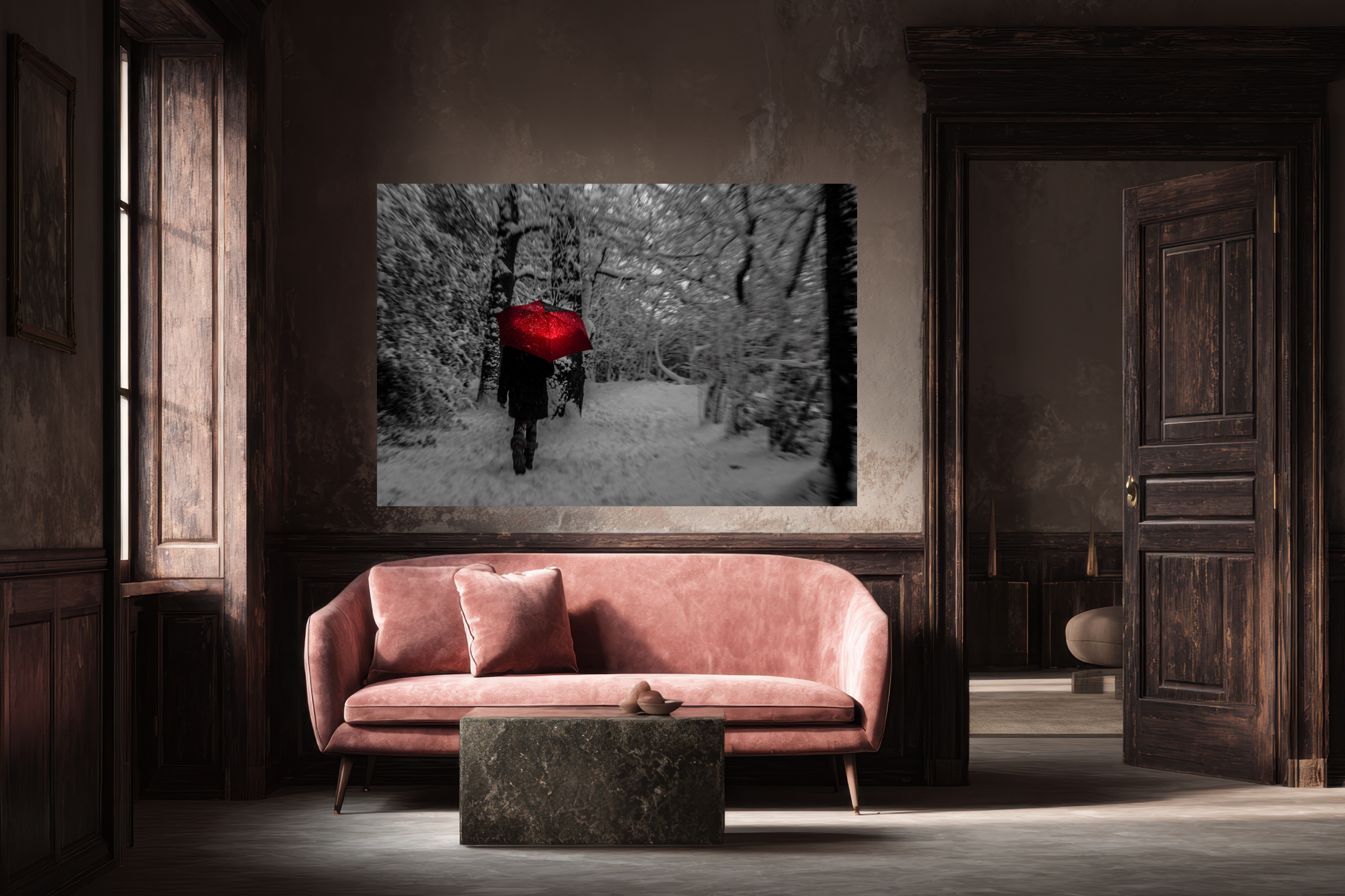A living room with dark wood paneling, a pink velvet sofa with a matching pillow, a small rectangular stone coffee table with a pair of shoes on top, and a large black and white wall art piece depicting a person walking in a snow-covered forest while holding a red umbrella.