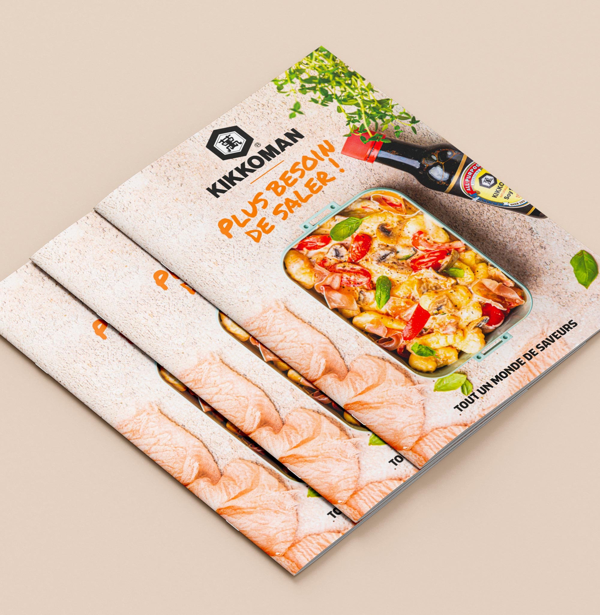 Brochure promotionnel de la marque Kikkoman présentant une image d'un plat de pâtes avec sauce, légumes et jambon, accompagnée d'une bouteille de sauce soja. Le texte en français dit 'Plus besoin de saler!
