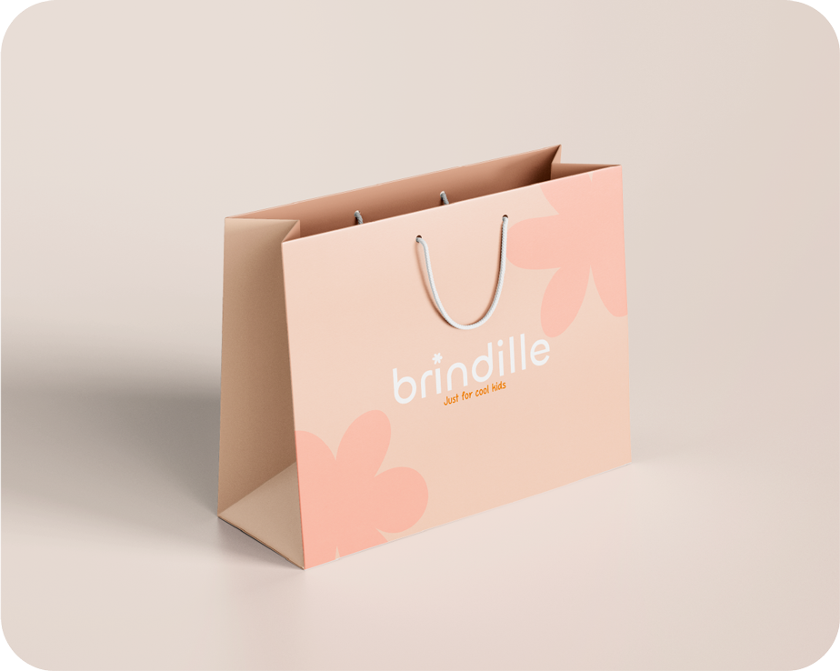 Sac en papier rose pâle avec des motifs floraux, marqué du nom 'brindille' et de la phrase 'Just for cool kids', avec une corde pour la poignée