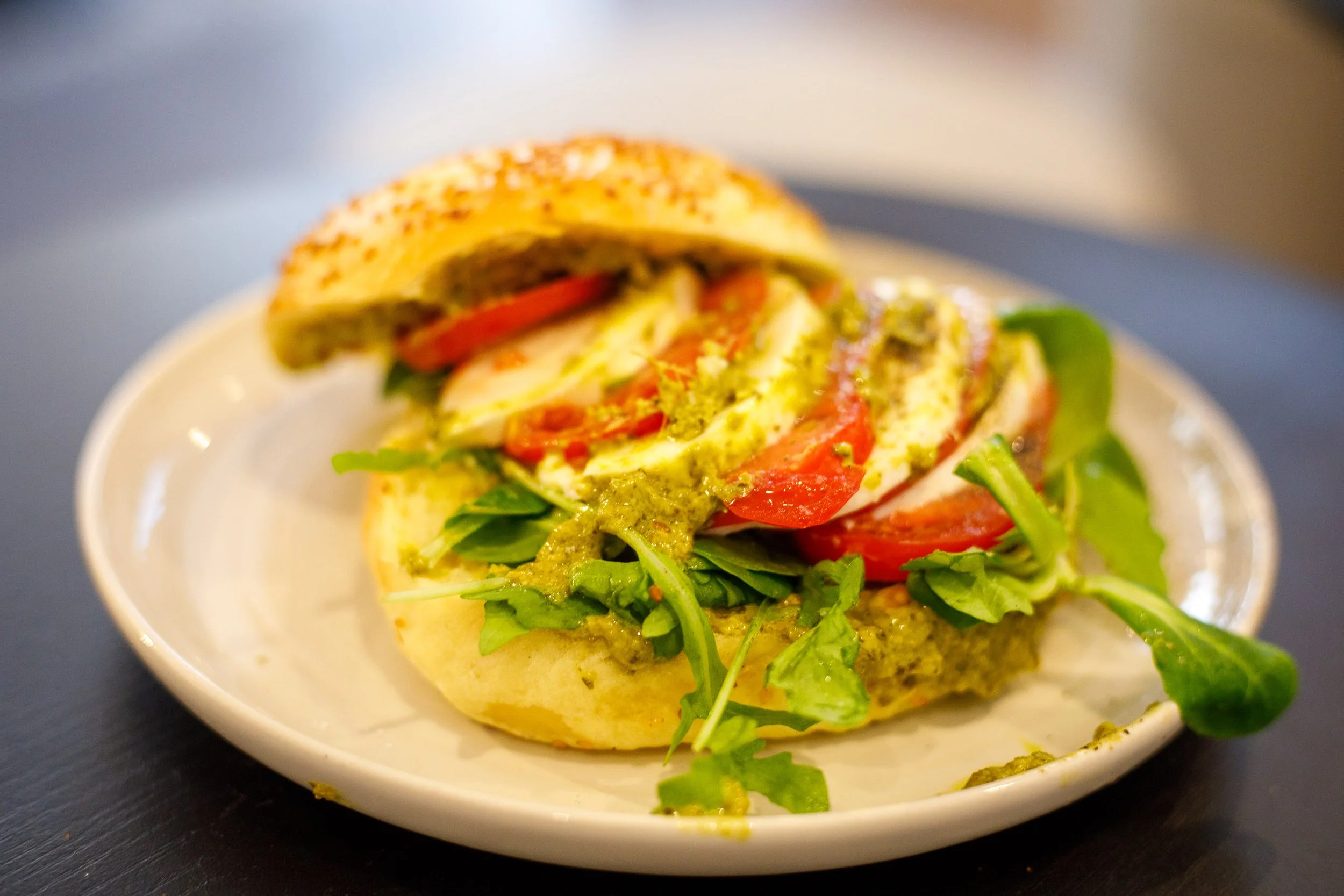 Sandwich avec œufs, tomates, pousses d'épinards et sauce verte, servi sur une assiette blanche