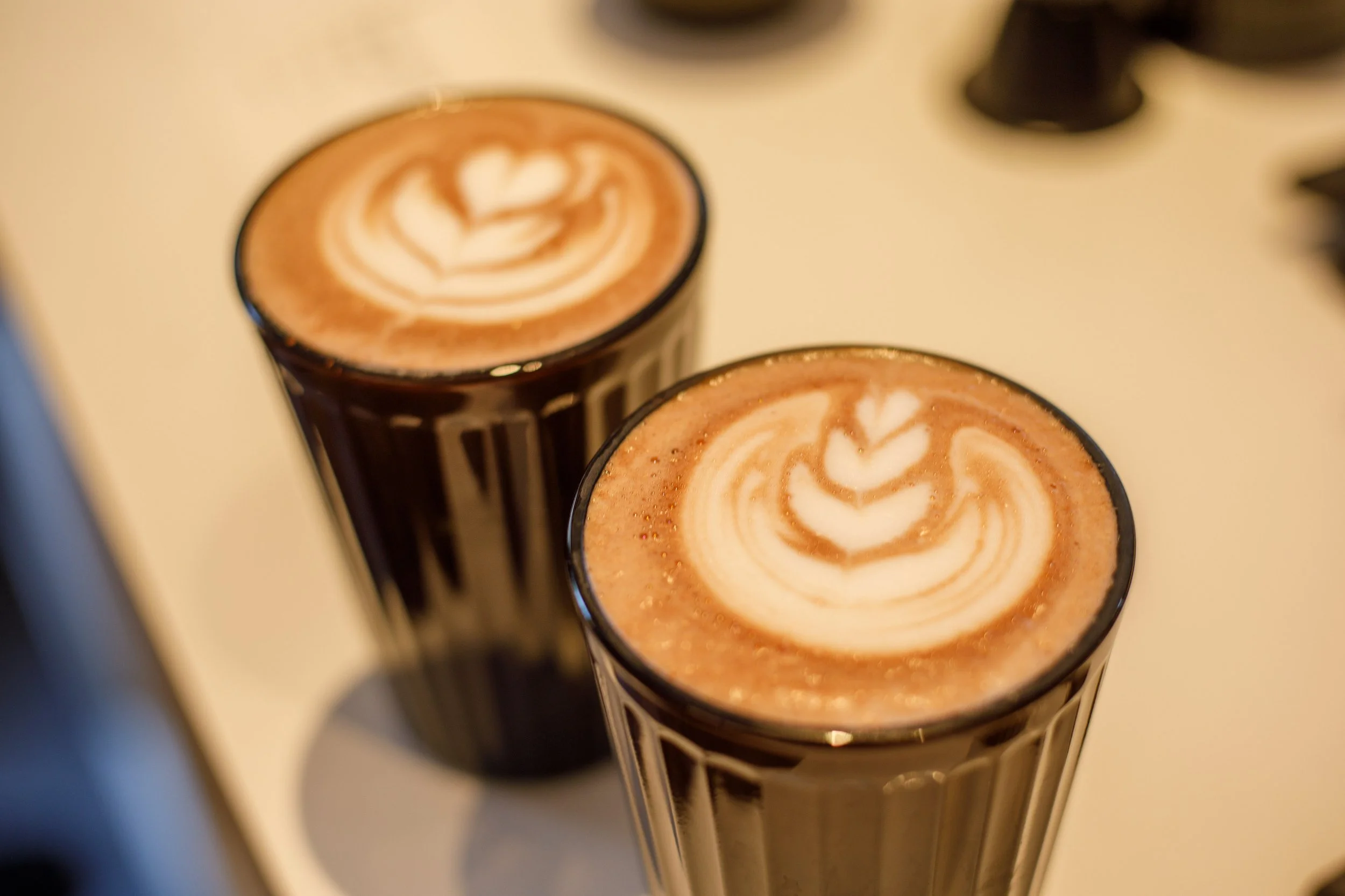 Deux verres de chocolats chauds garnis de latte art en forme de cœurs.