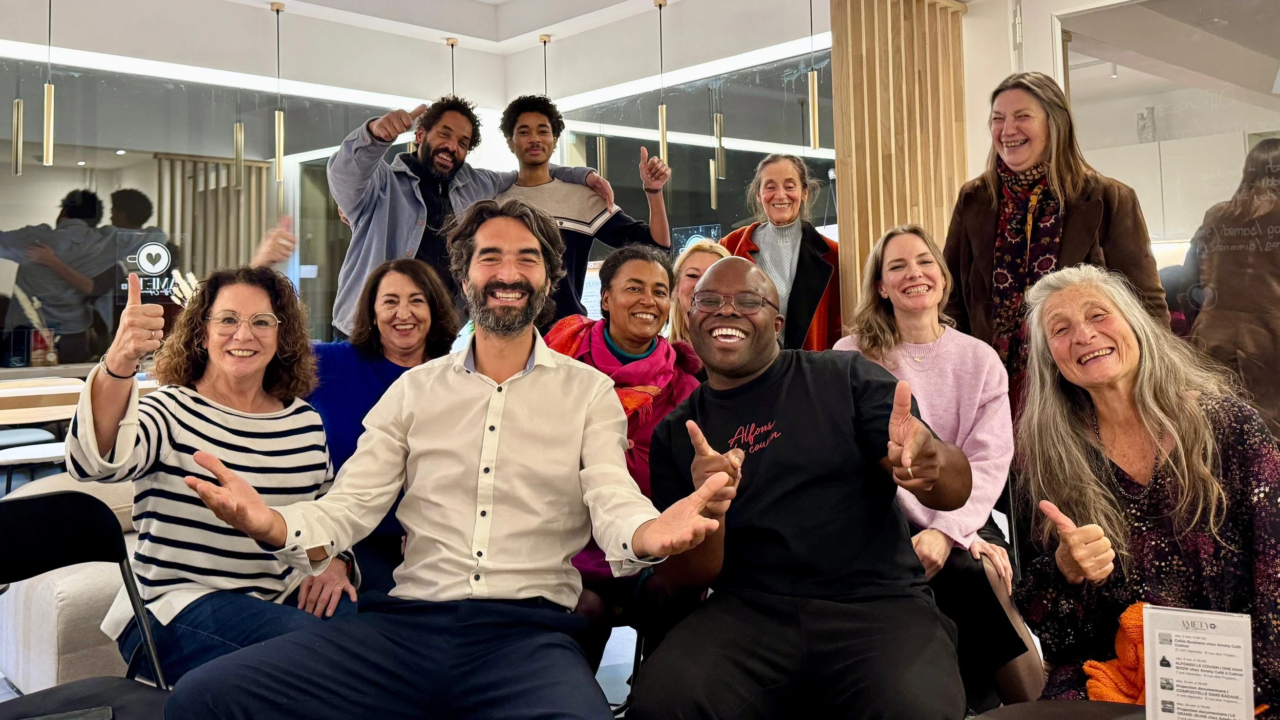 Groupe de personnes souriantes et souriantes lors d'une réunion ou d'un rassemblement social, posant pour la photo dans une ambiance chaleureuse et conviviale.