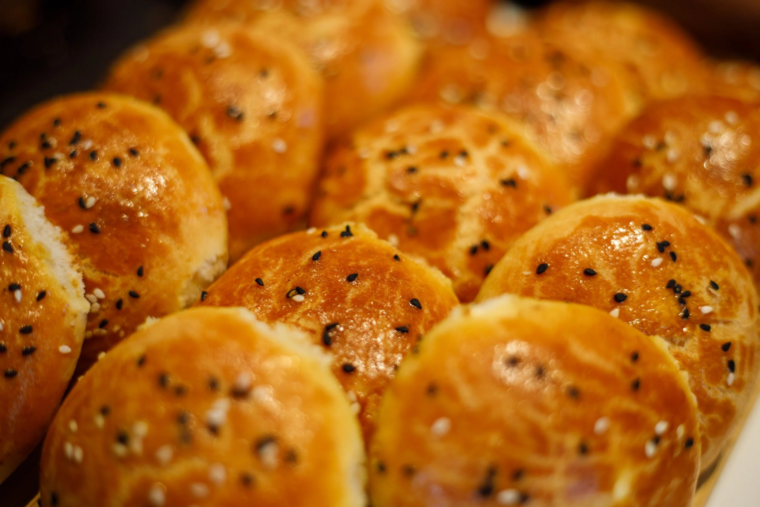 Petits pains dorés avec des graines de sésame noir et blanc dessus, chaud et appétissant avec du fromage feta à l'intérieur.