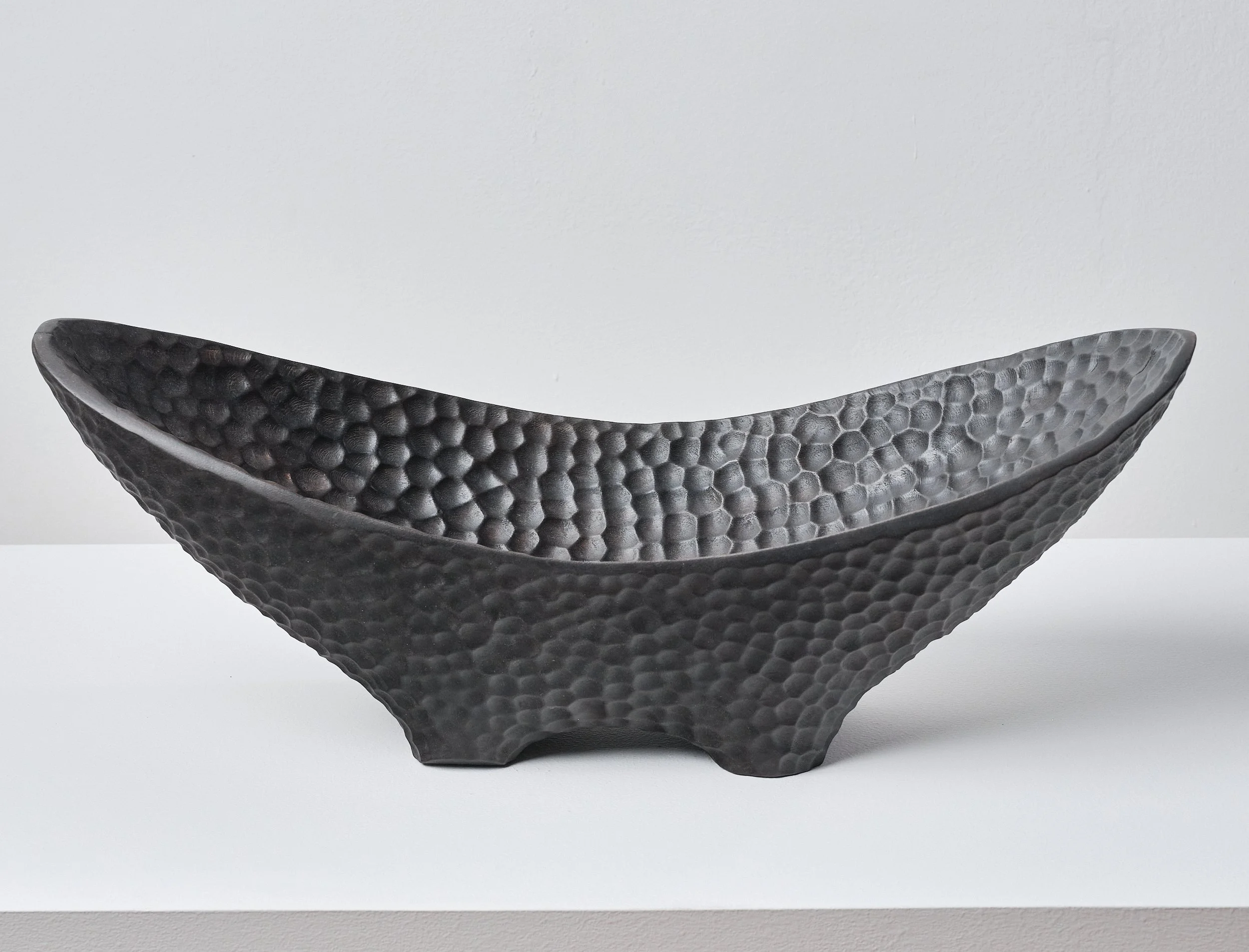 Black hammer textured bowl made from scorched and waxed London Plane timber with an organic shape on a white surface against a plain background.