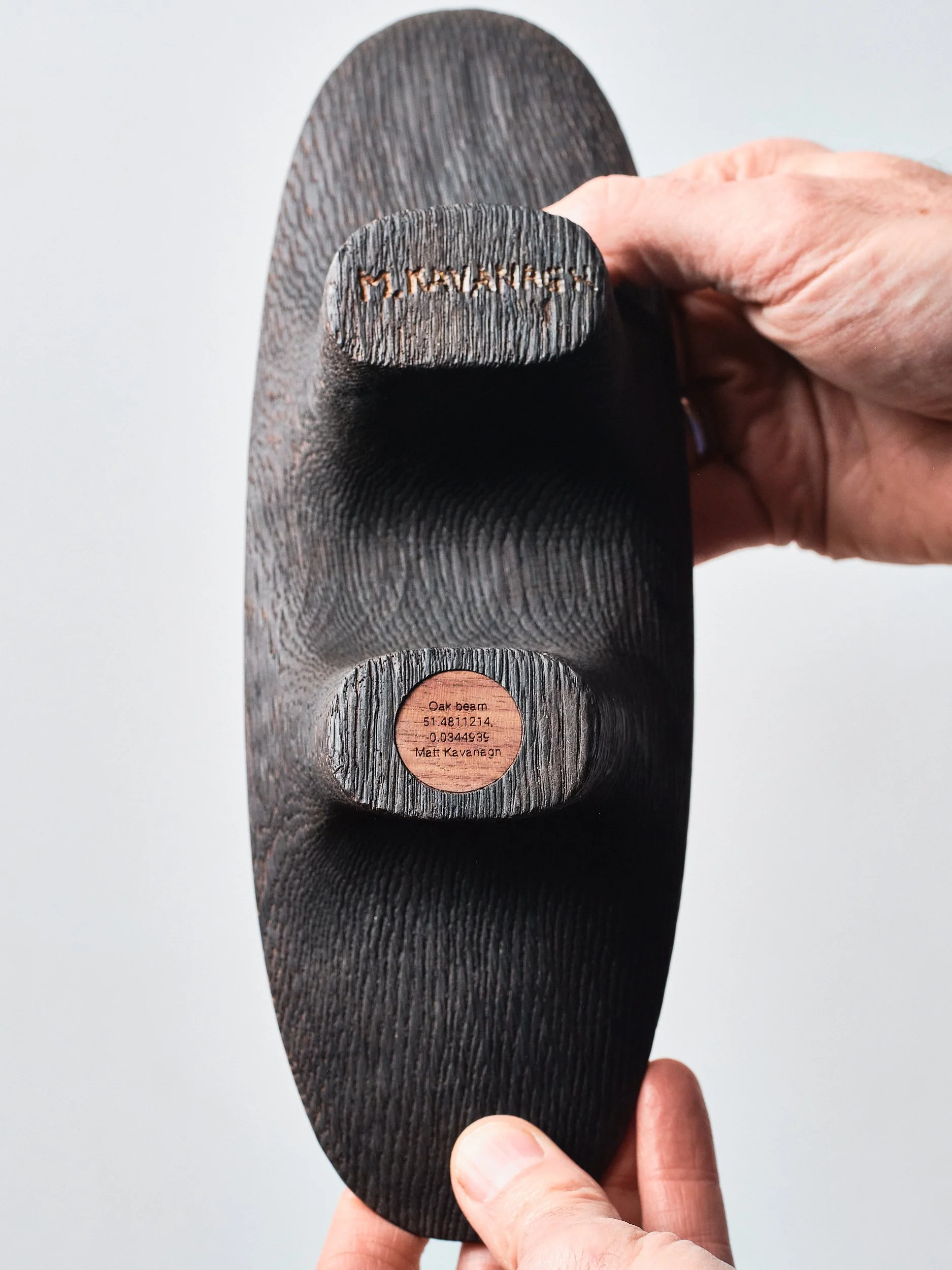 Close-up of the bottom of a wooden sculpture with engraving of the coordinates of where the timber location and the artists signature