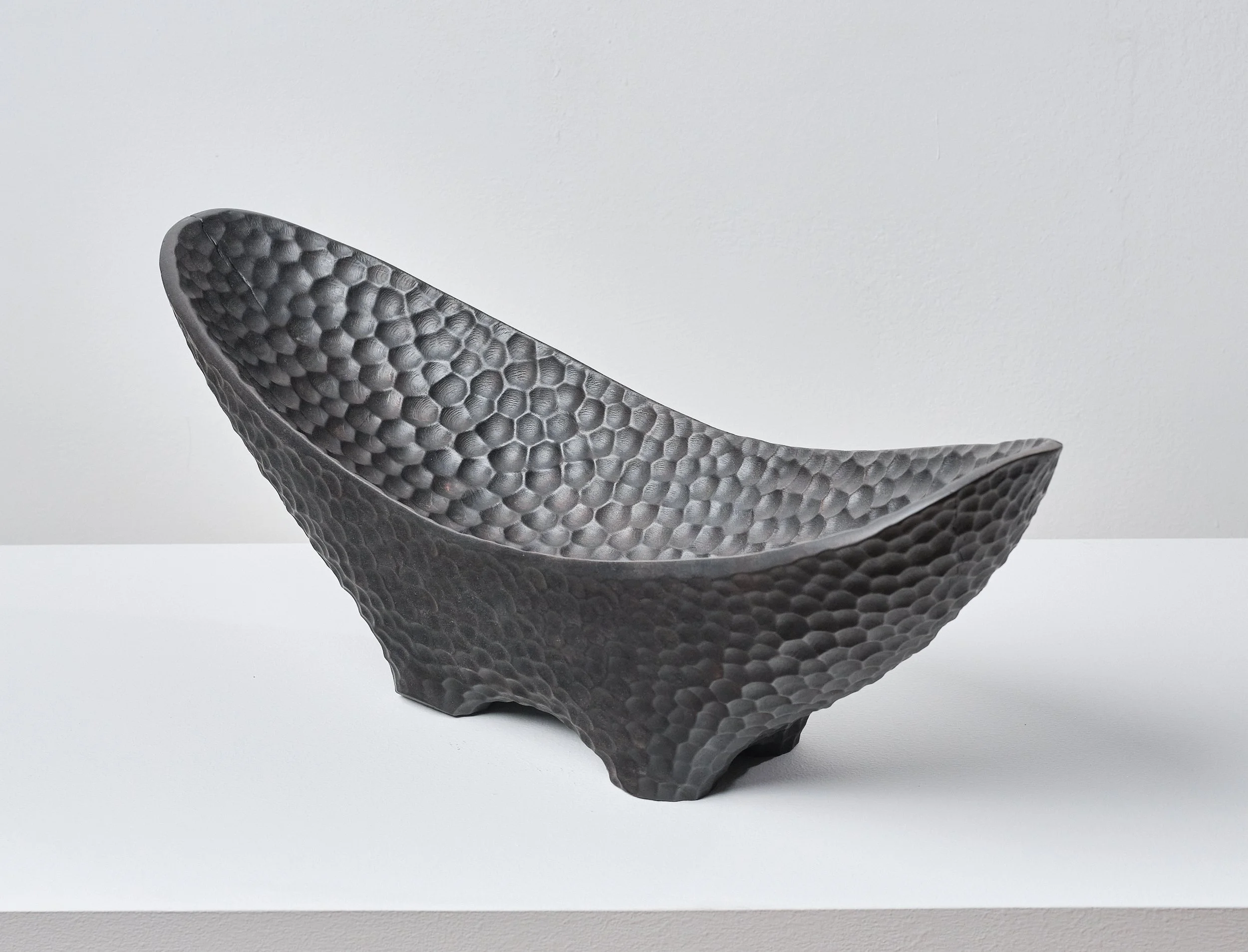 Black textured bowl made from scorched and waxed London Plane timber with an organic shape on a white surface against a plain background.