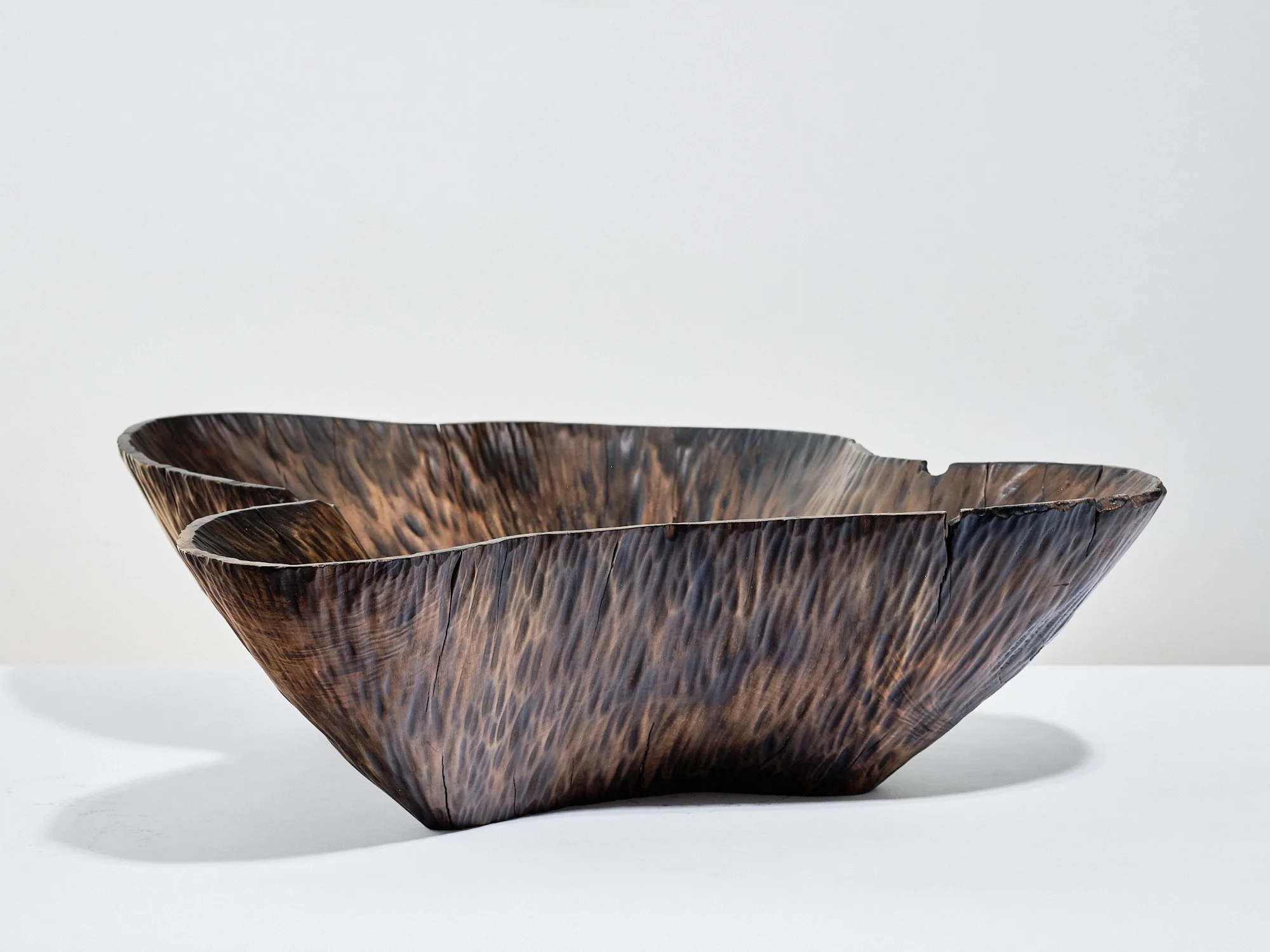 A dark conker-brown, rib-textured, organic-shaped wooden bowl hand-crafted from horse chestnut, on a white surface against a plain white background.