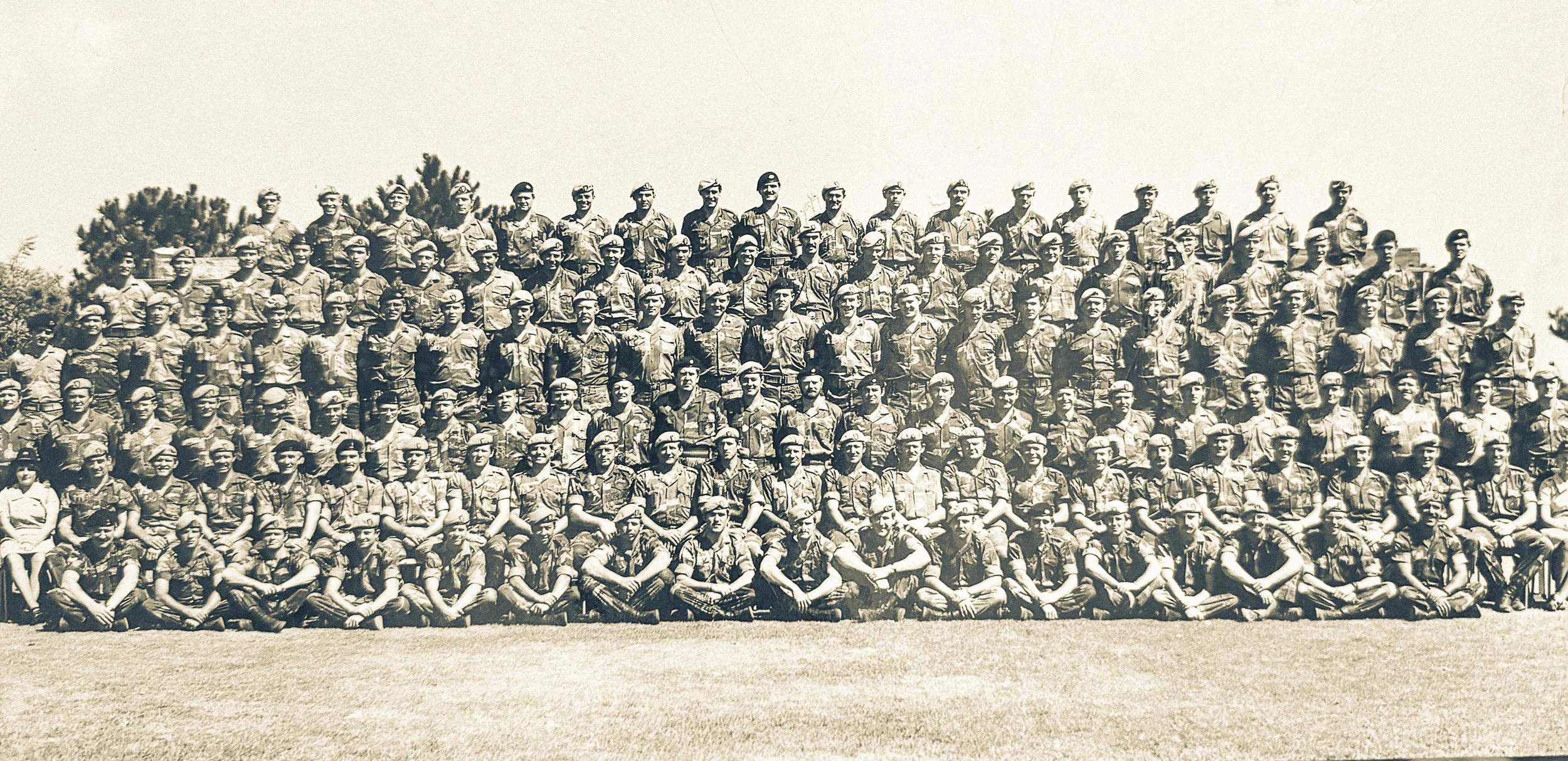 Group of soldiers in uniform posing outdoors in a large assembly