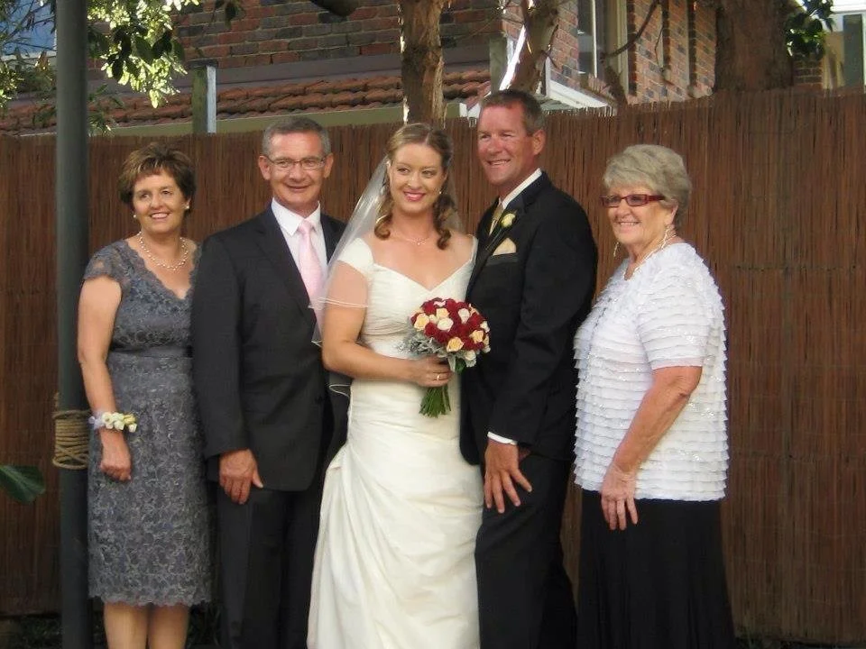 A wedding photo of a bride and groom with three women, celebrating outdoors.