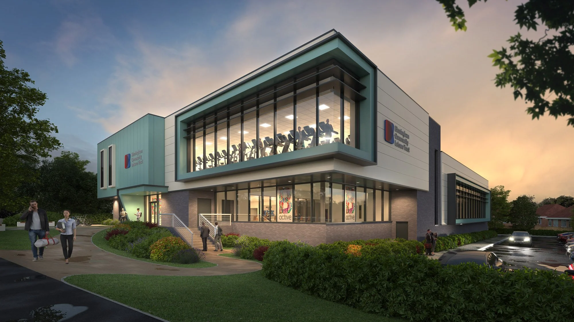 A modern two-story building with large glass windows, exercise equipment visible inside, surrounded by greenery, parked cars, and people walking outside during sunset.