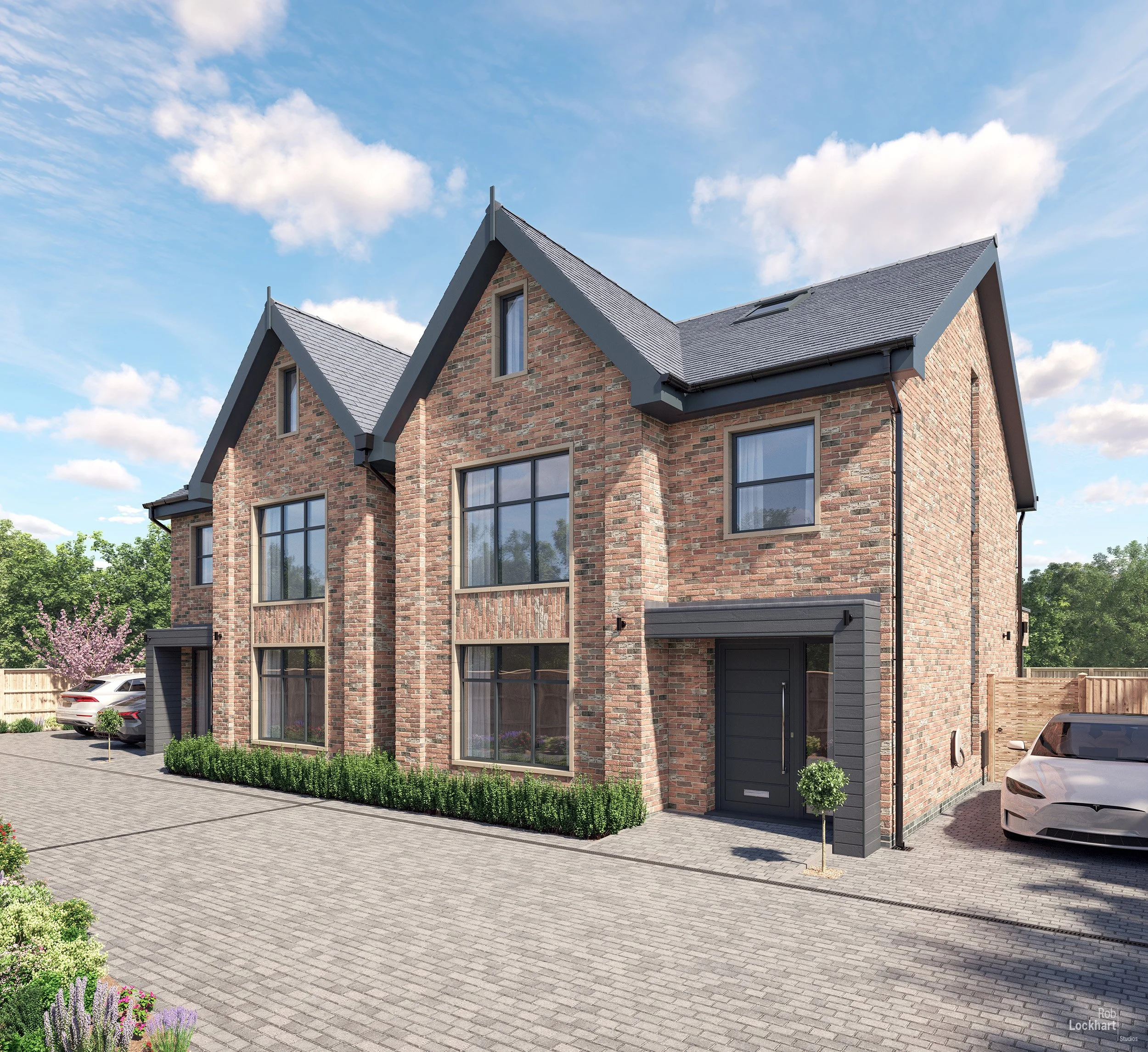 A modern two-story brick residential building with gabled roof and large windows, surrounded by a paved driveway and landscaped greenery, under a blue sky with clouds.