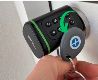 A person's hand holding a keychain with a fuse box remote control, pressing a button to turn the fuse box on or off.
