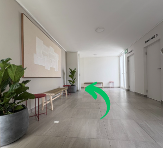Empty hallway with potted plants, benches, and artwork on the wall in a building corridor.
