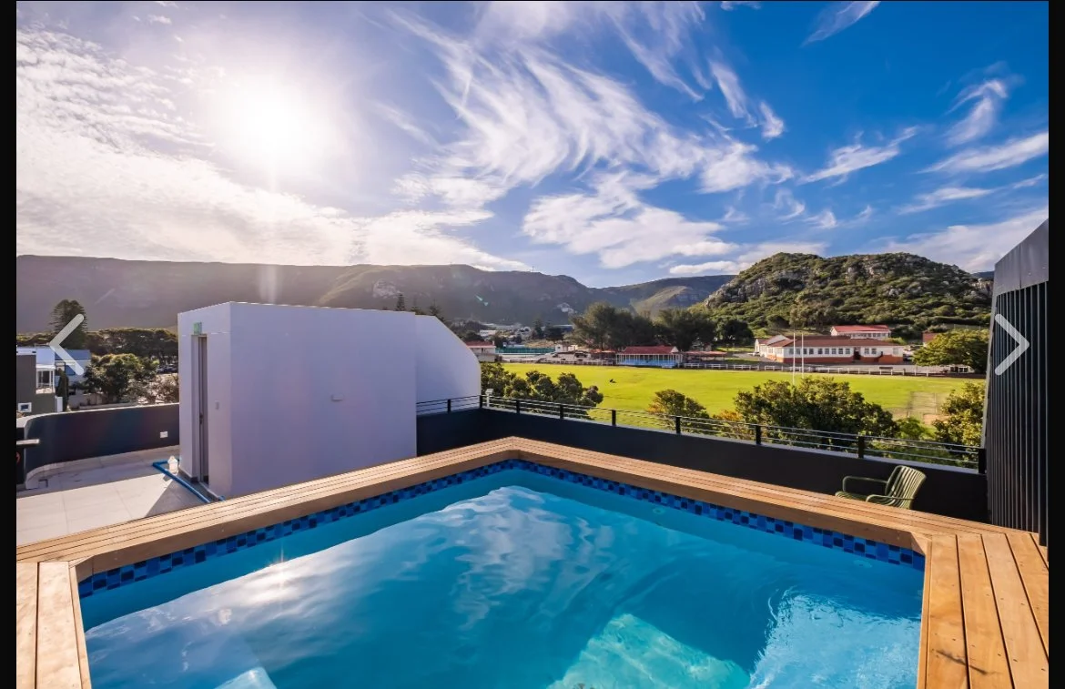 Modern rooftop pool with mountain and green landscape view on a sunny day.