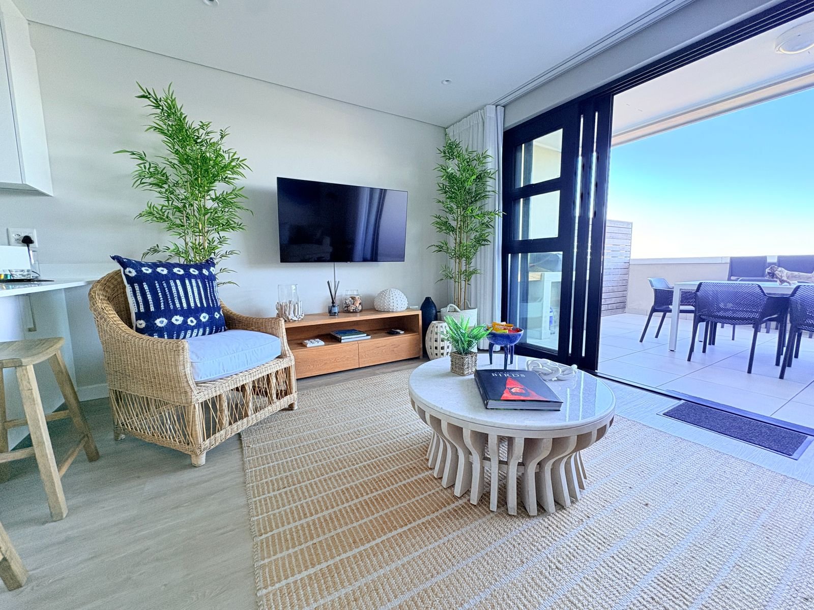 Living room with smart TV and large sliding doors opening to a sea view patio with BBQ - The View, self-catering apartment