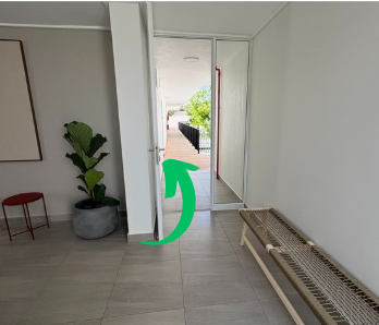 Open door leading outside, with a small black railing and greenery visible beyond