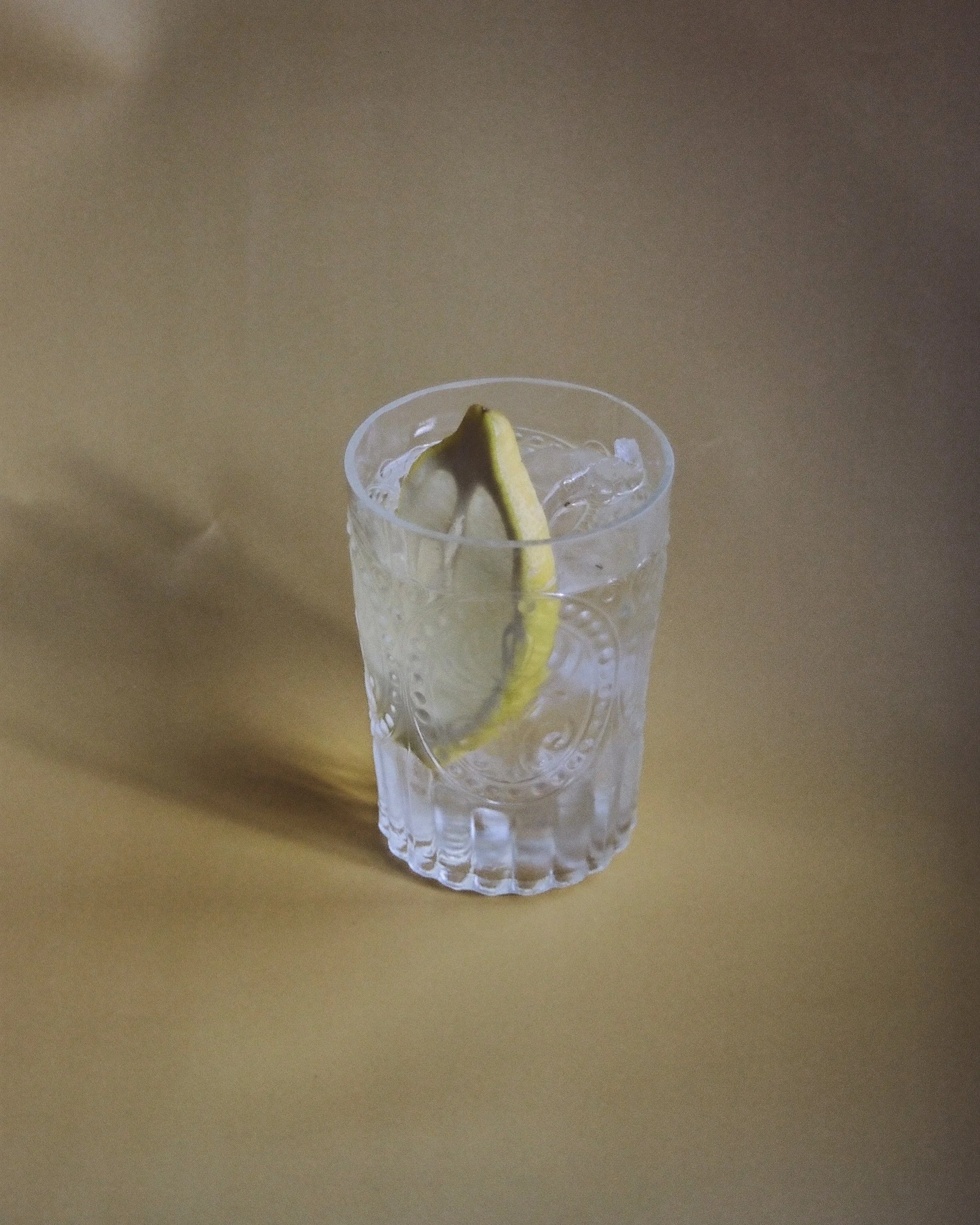 A glass of water with ice and a slice of lemon.