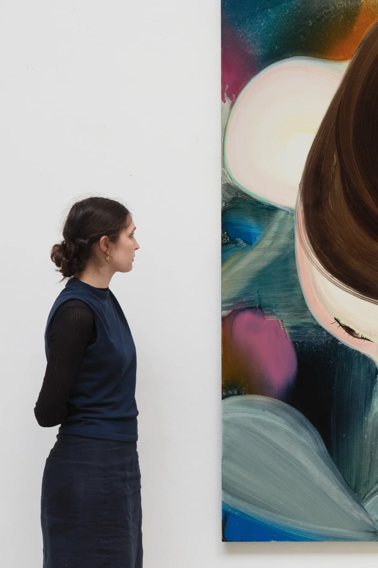 A woman observing an abstract painting in an art gallery.
