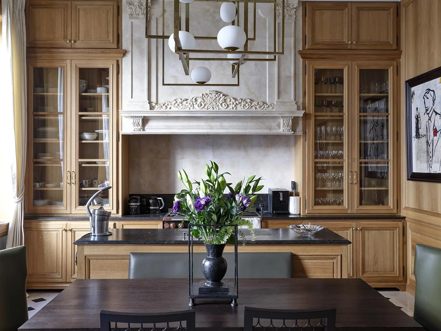 Kitchen with wooden cabinets, black countertop, and a flower vase with purple flowers on the dining table.