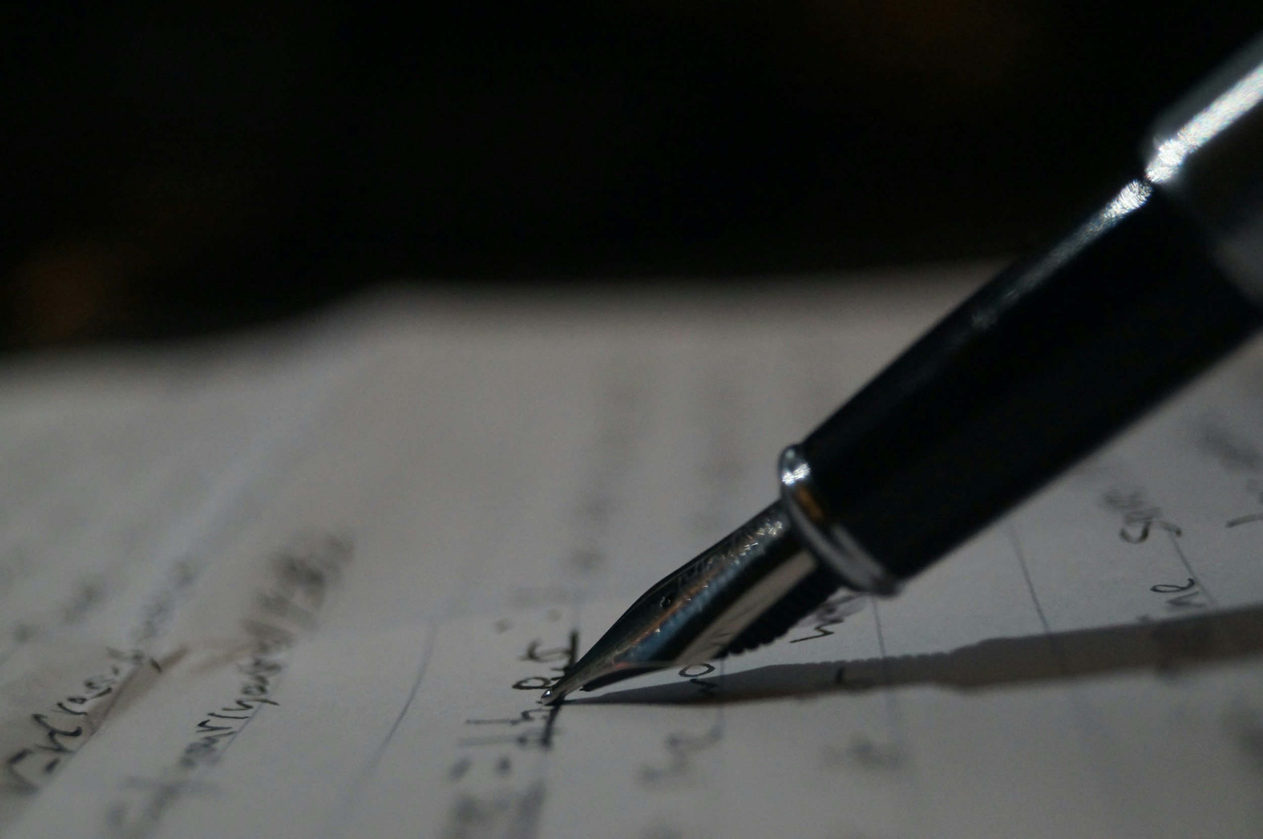 A black pen writing on a sheet of paper with handwritten notes.