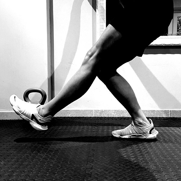 Person stretching their legs while wearing athletic shoes indoors.