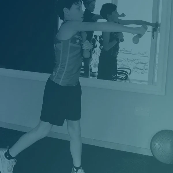 Young boy doing strength training with weights, shoulder arm exercise.