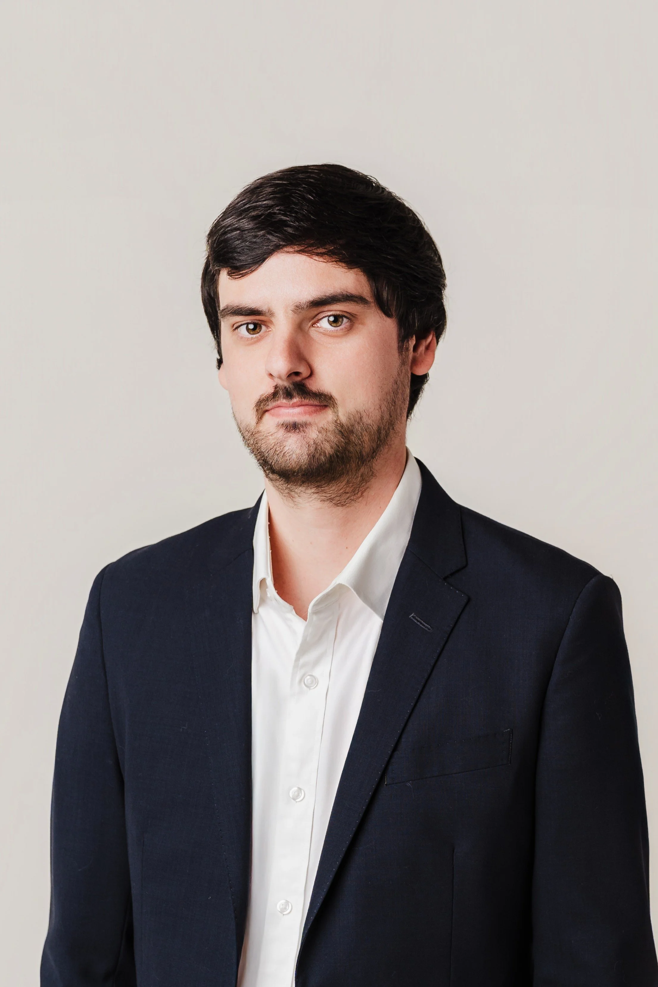 Reed Fincher, Executive Director, headshot standing in a black blazer in front of a cream background.