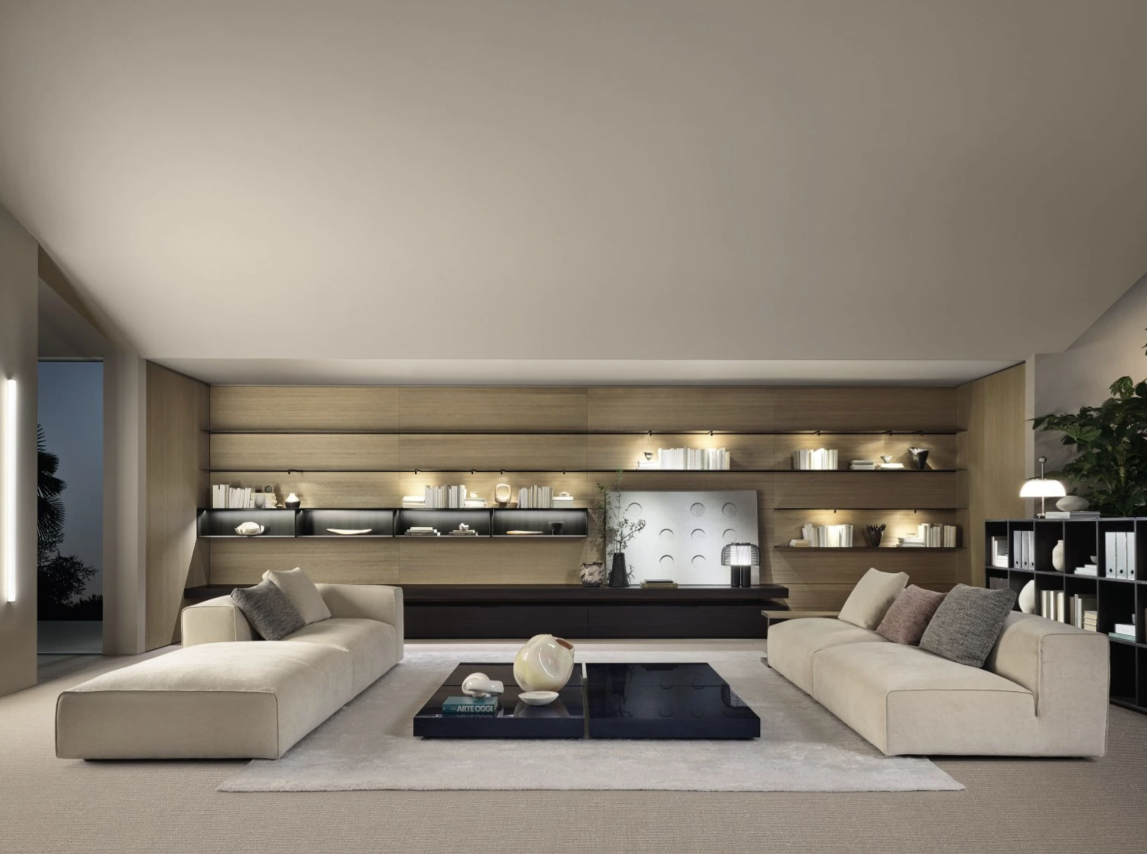 Modern living room with beige sofas, a black coffee table with decorative objects, wooden wall with built-in shelves, and a bookcase on the right, illuminated with soft lighting.