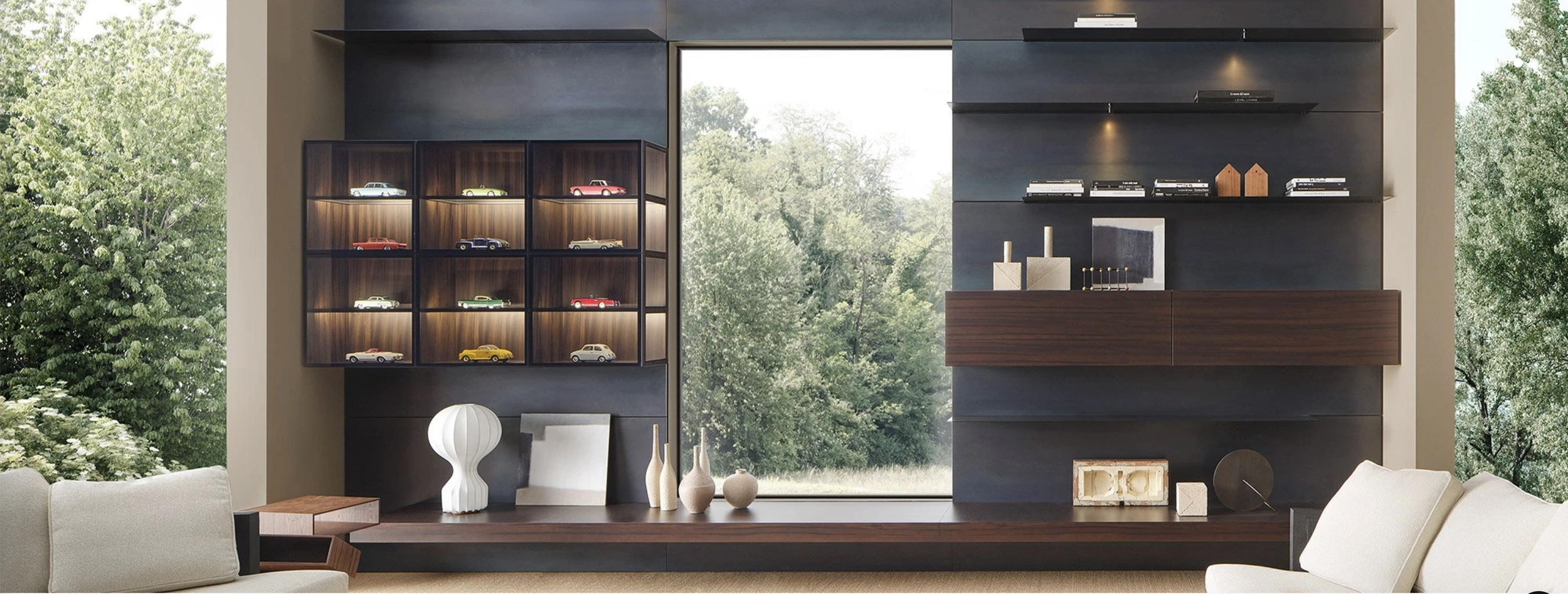 Modern living room with a large window, dark wood shelves displaying small decorative cars, and minimalist decor including vases and artwork.