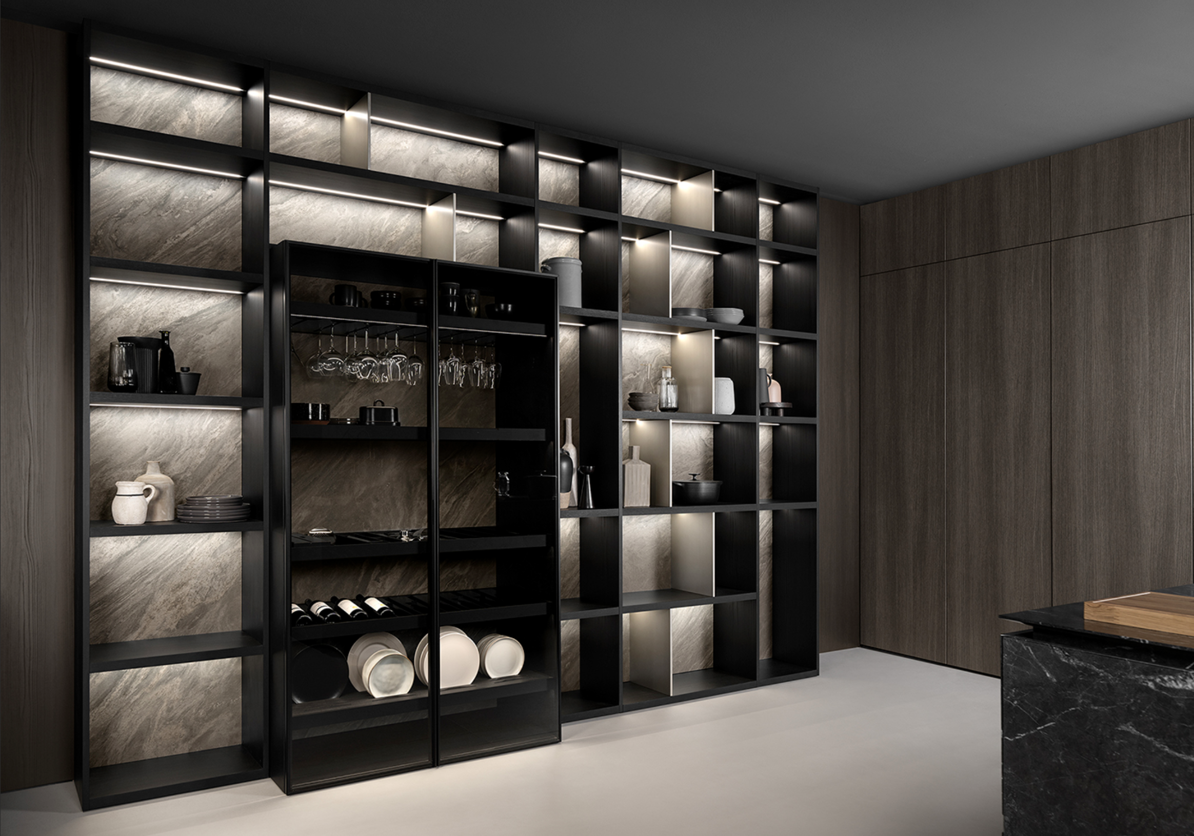 Modern kitchen shelving unit with black and beige compartments, illuminated for display of dishes, glasses, and decorative items in a minimalist style.