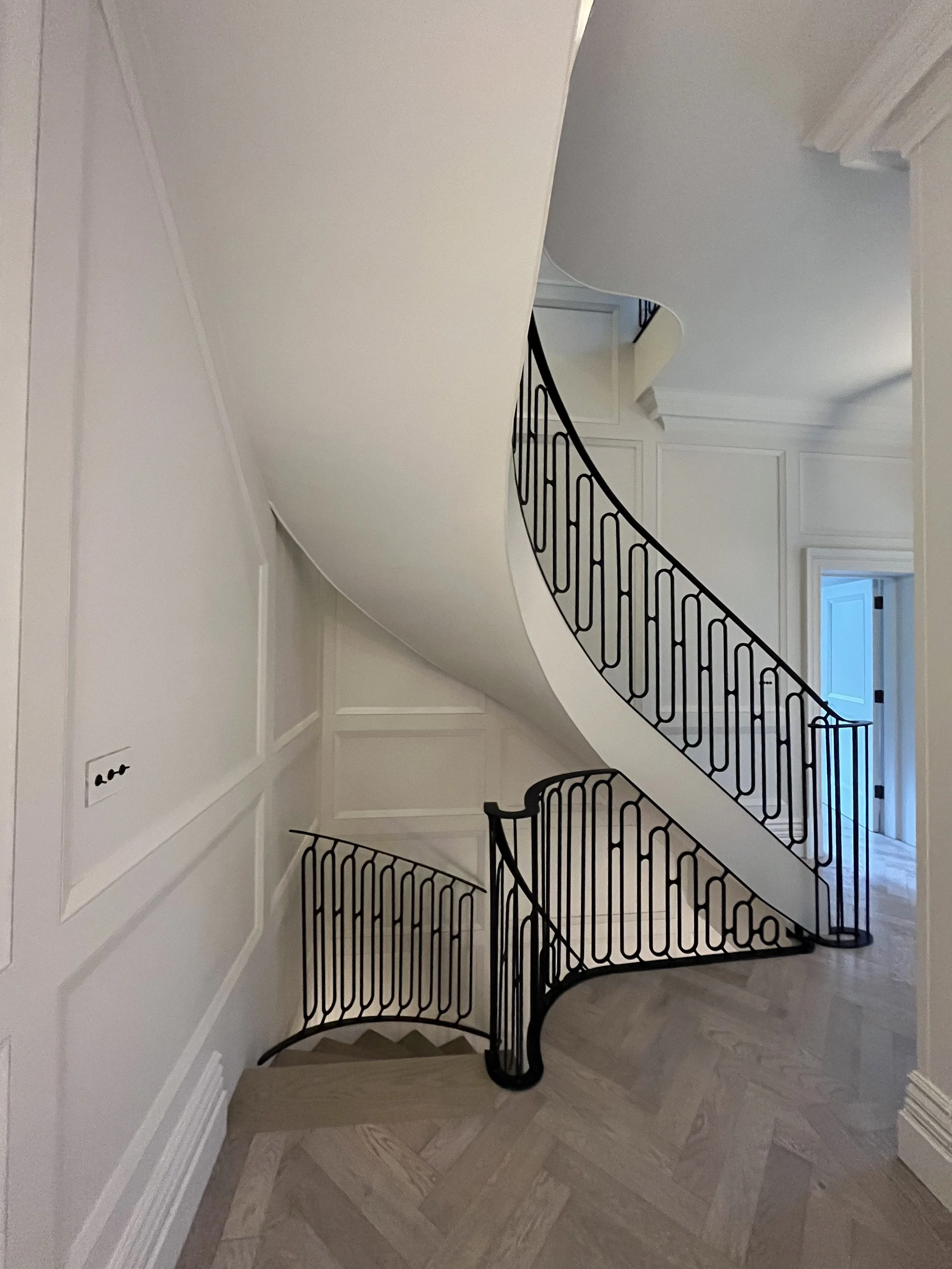 Interior staircase with black wrought iron railing and white walls in a house.