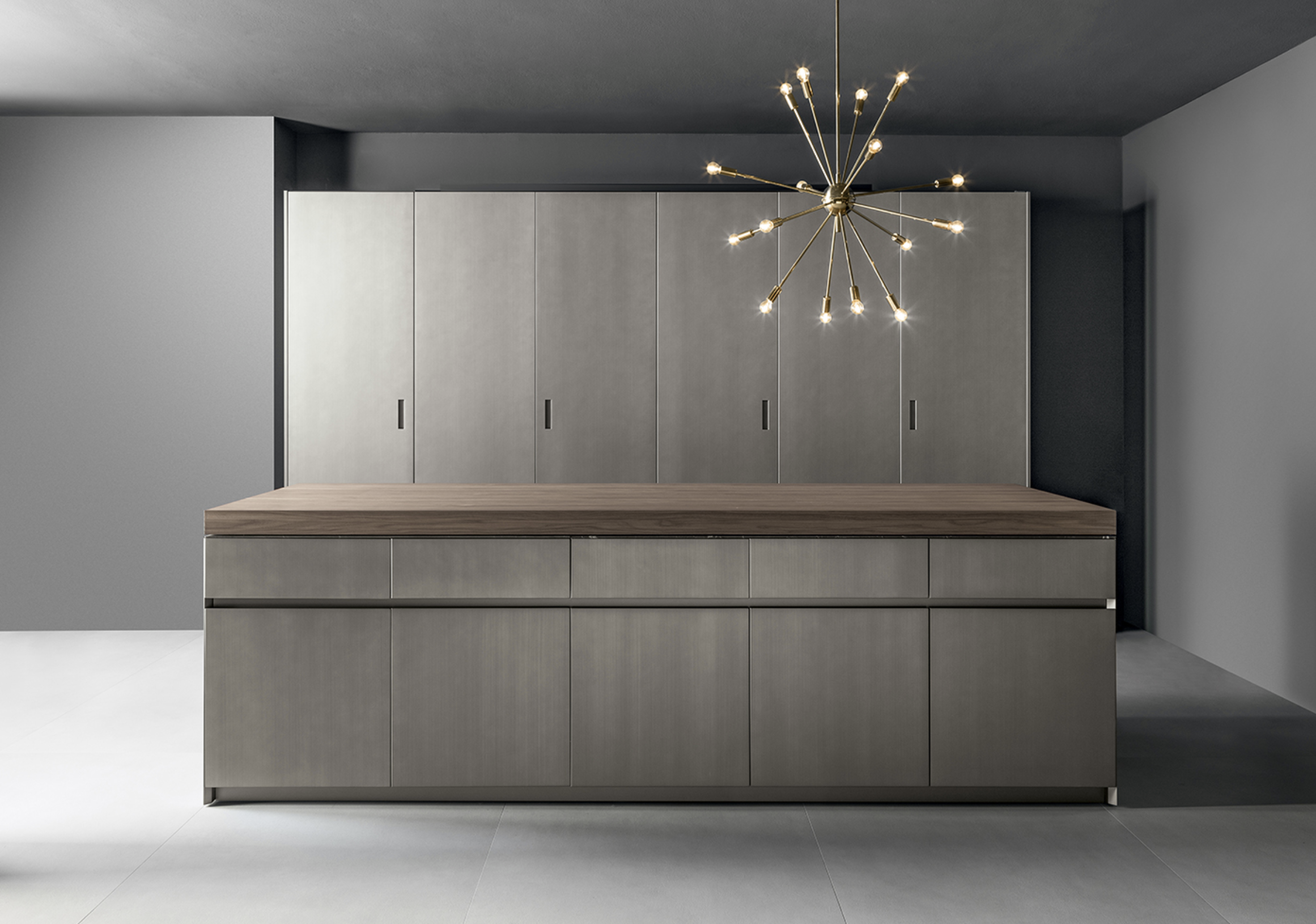 Modern kitchen with gray cabinets and a wooden countertop, featuring a gold starburst pendant light fixture in a minimalist space.