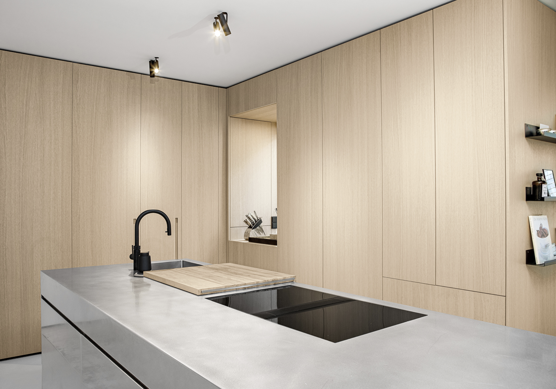 Modern kitchen with light wood cabinets, a white countertop, a black faucet, and an induction cooktop.