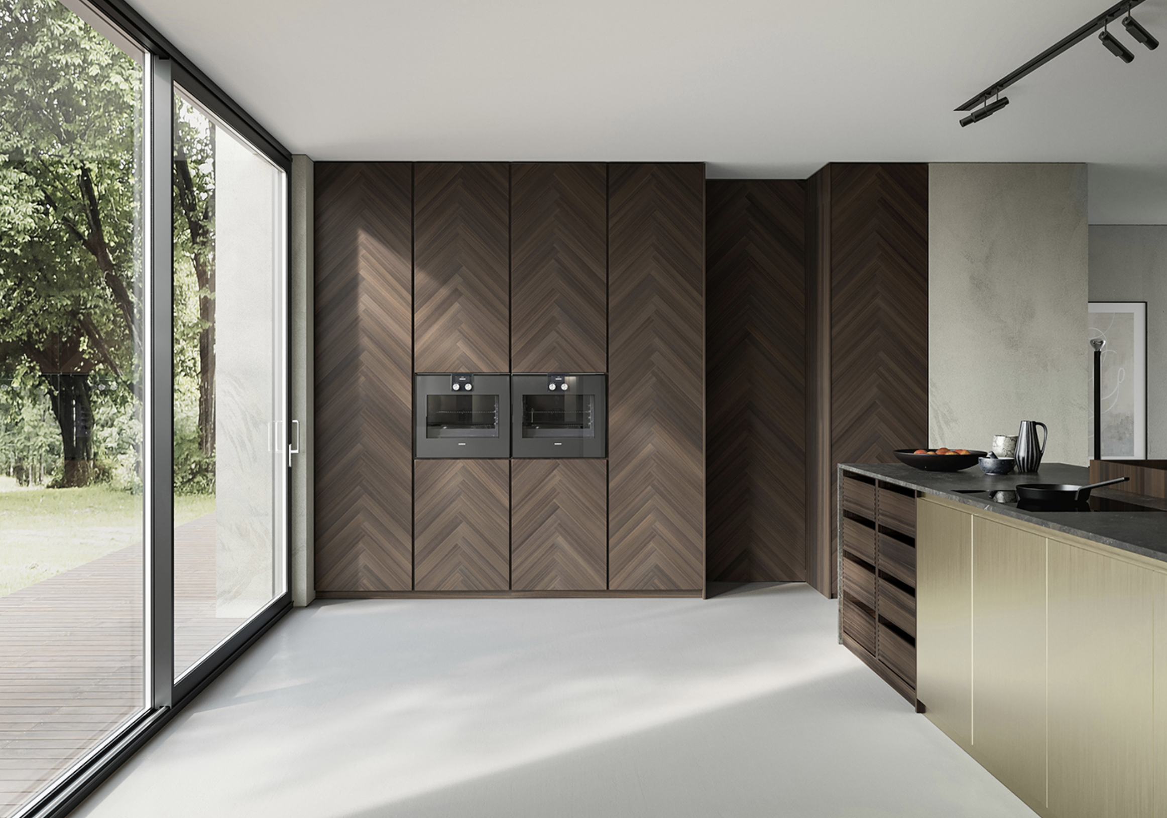 Modern kitchen with large glass sliding door, dark wood cabinets, built-in ovens, and a kitchen island with a black countertop, also showing outside greenery.