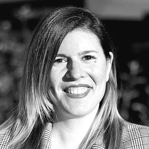 A AI innovation woman leader with long hair and a checkered shirt smiling in black and white.