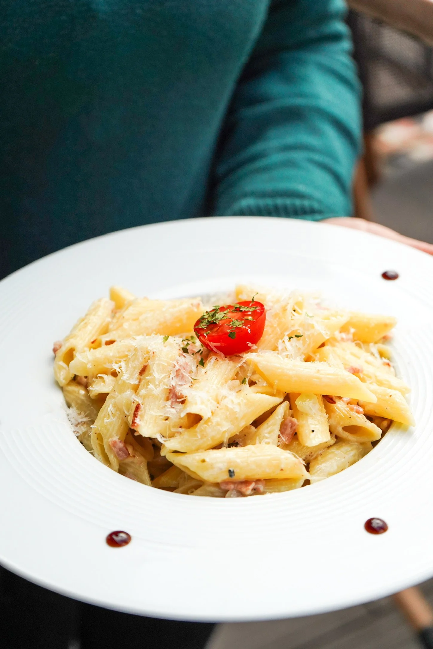 Assiette de pâtes à la crème, avec morceaux de jambon, garnie de fromage et de persil.