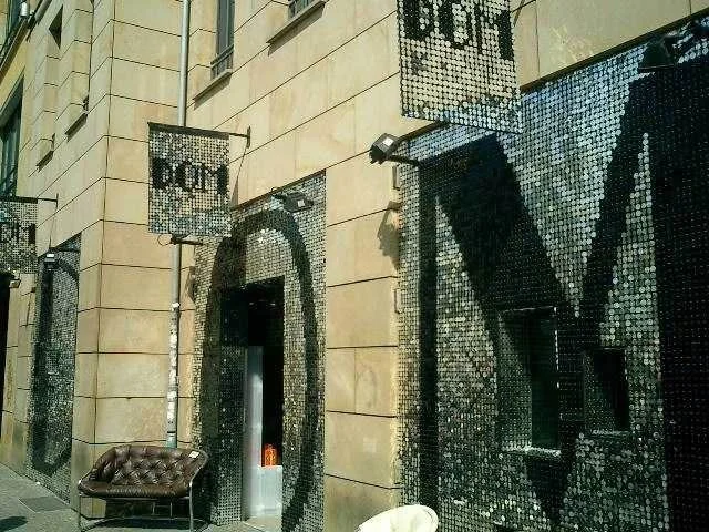 Schmuckverzierte Wand mit Buchstaben und Noten, eine Bank und ein Sessel davor.