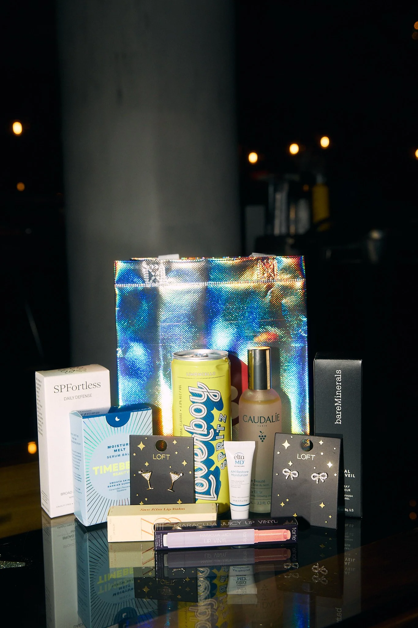 An assortment of beauty and skincare products displayed on a reflective surface with a holographic background.