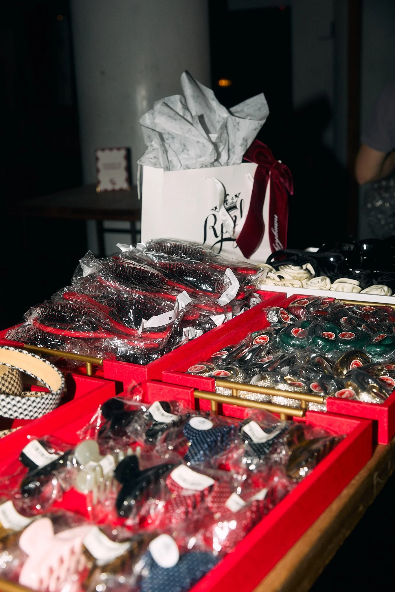 Display of hair accessories, including headbands, hair clips, and hair ties, in red trays at a store or boutique.