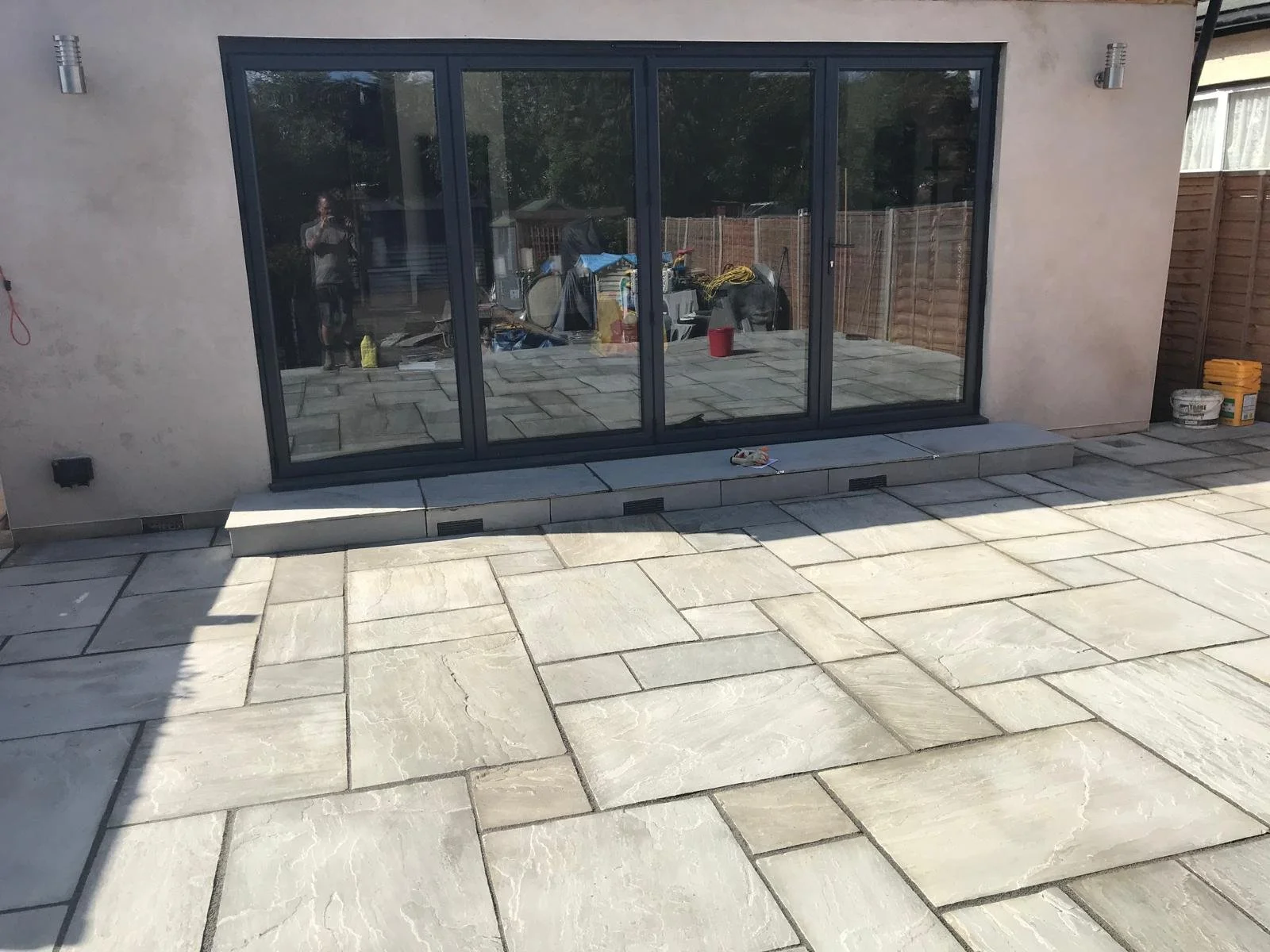 Patio renovation featuring a new step with air bricks for ventilation and a stylish Indian sandstone surface.