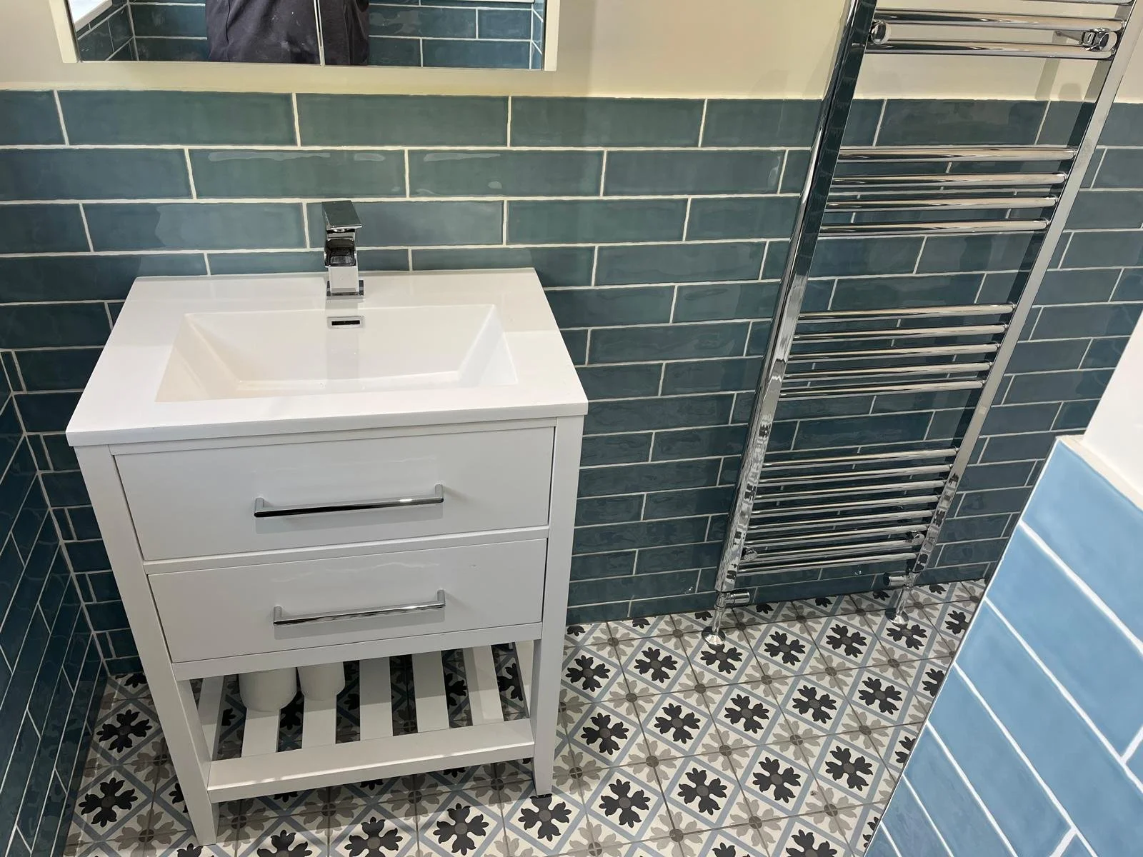 Modern vanity unit and towel radiator installation improving storage and comfort in the bathroom.