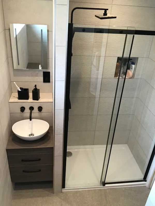 Full bathroom remodel with a modern walk-in shower and custom vanity unit, maximising storage and functionality.