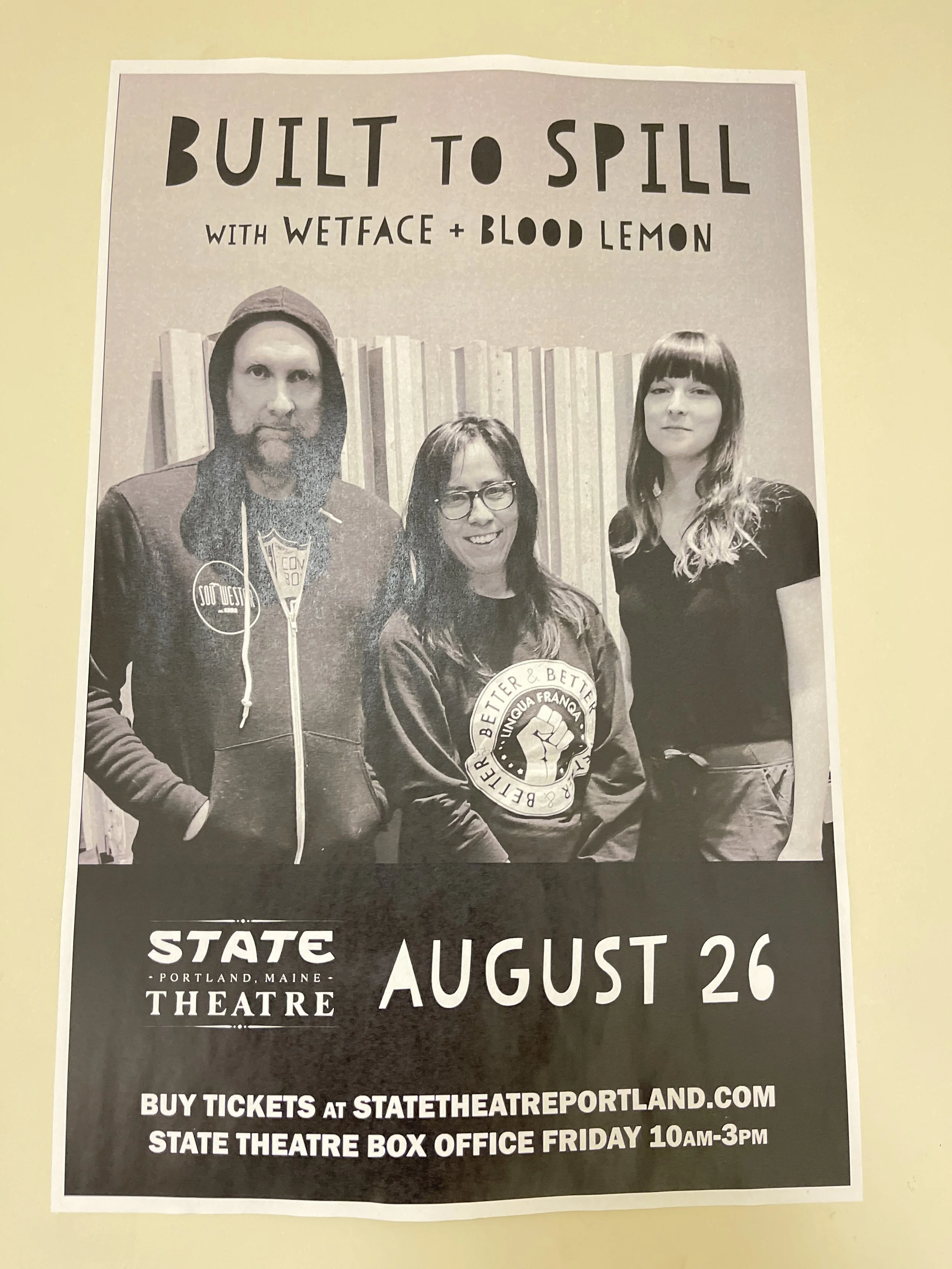 Black and white promotional poster for a performance called 'Built to Spill' with Wetface and Blood Lemon at the State Theatre in Portland, Maine, on August 26. The poster features three people standing in front of a wall with vertical striped paneli