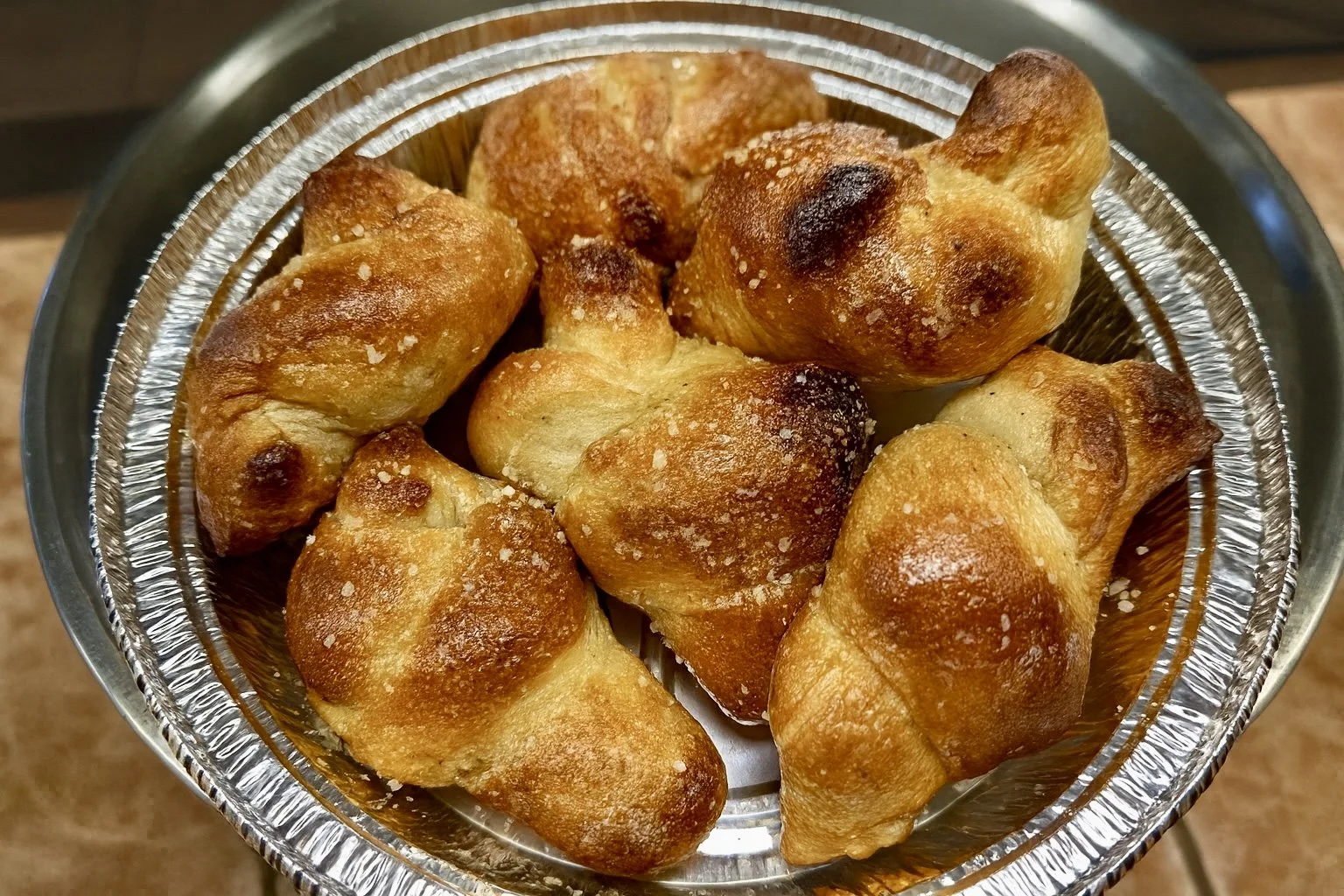 Close-up of several fried garlic knots in a metal basket.