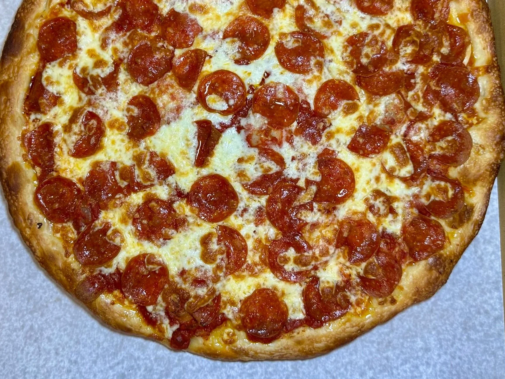 A pepperoni pizza in a cardboard delivery box on a silver table.