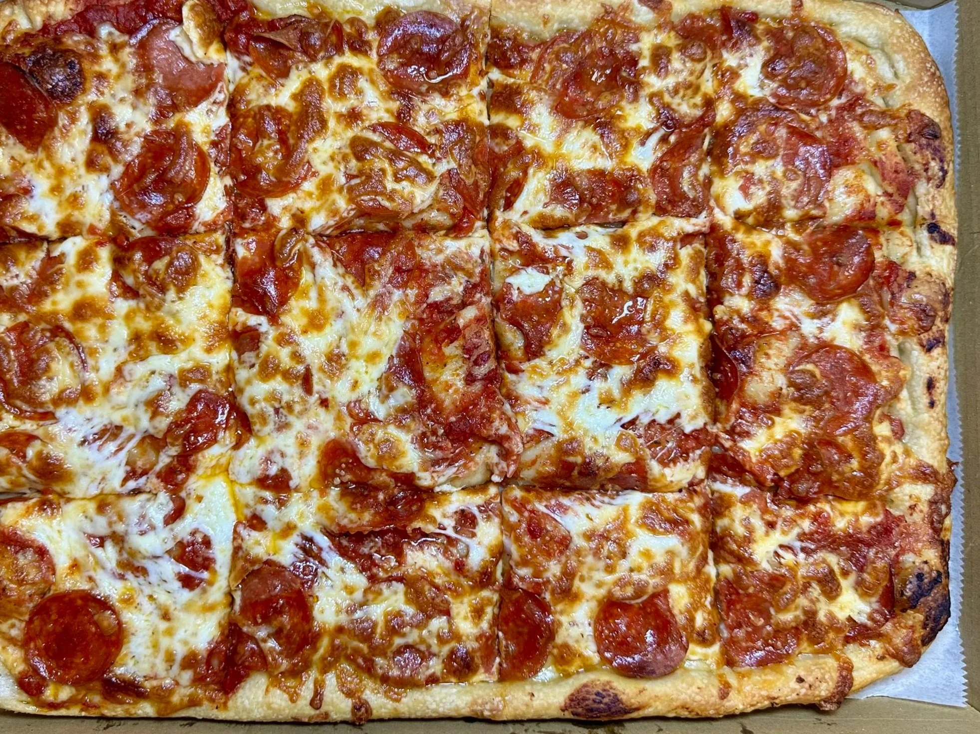 A rectangular pepperoni pizza with cheese in a cardboard box.
