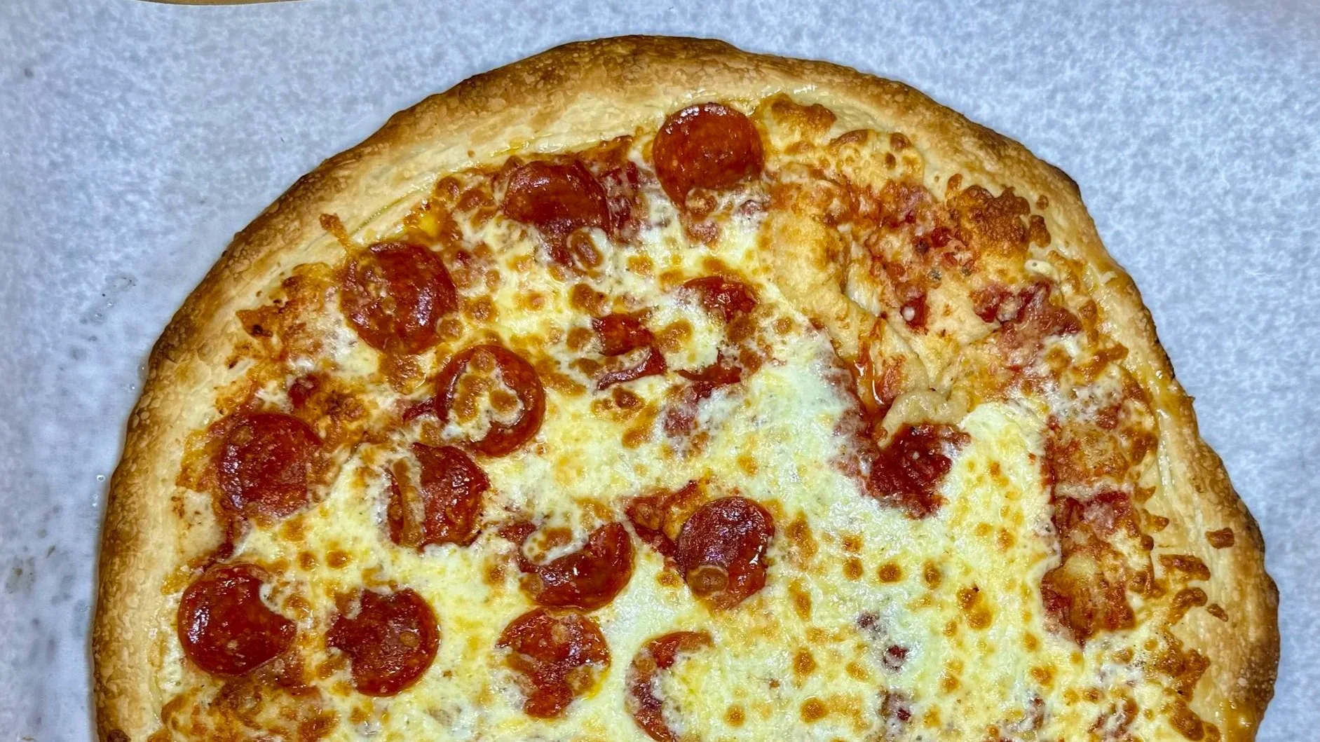 Cheese and pepperoni pizza on a pizza box with parchment paper