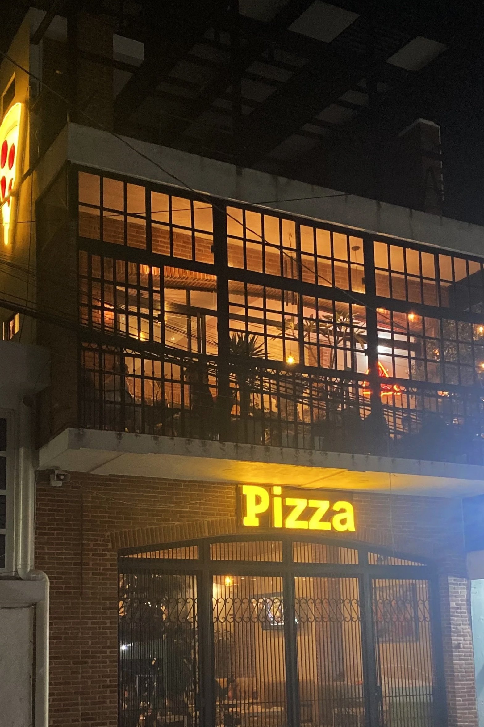 Fachada de un restaurante de pizza con servidor de noche.